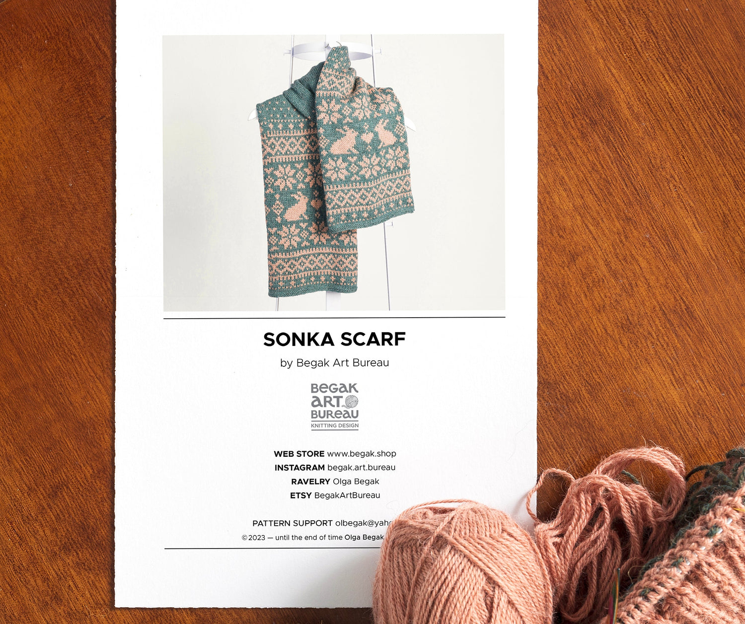 Printed knitting pattern instrustion with yarn balls on antique wooden table surface