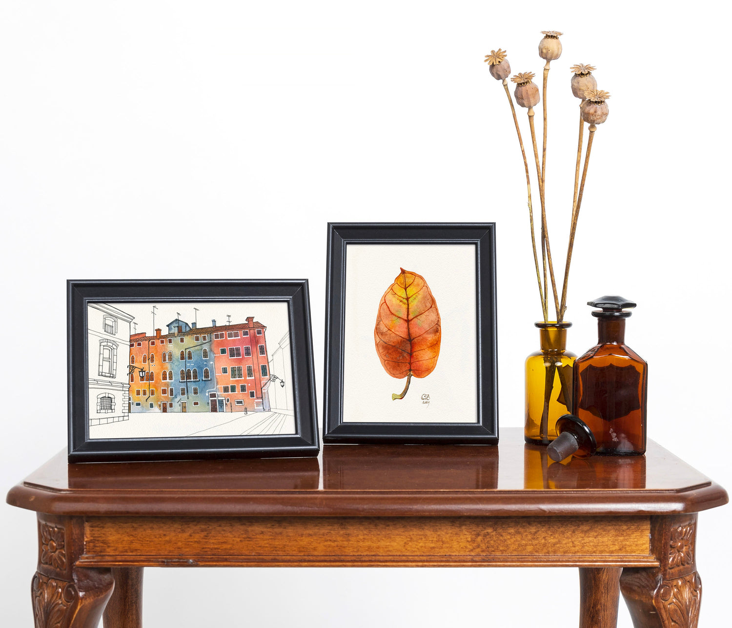 Watercolor artworks in frames on antique wooden table