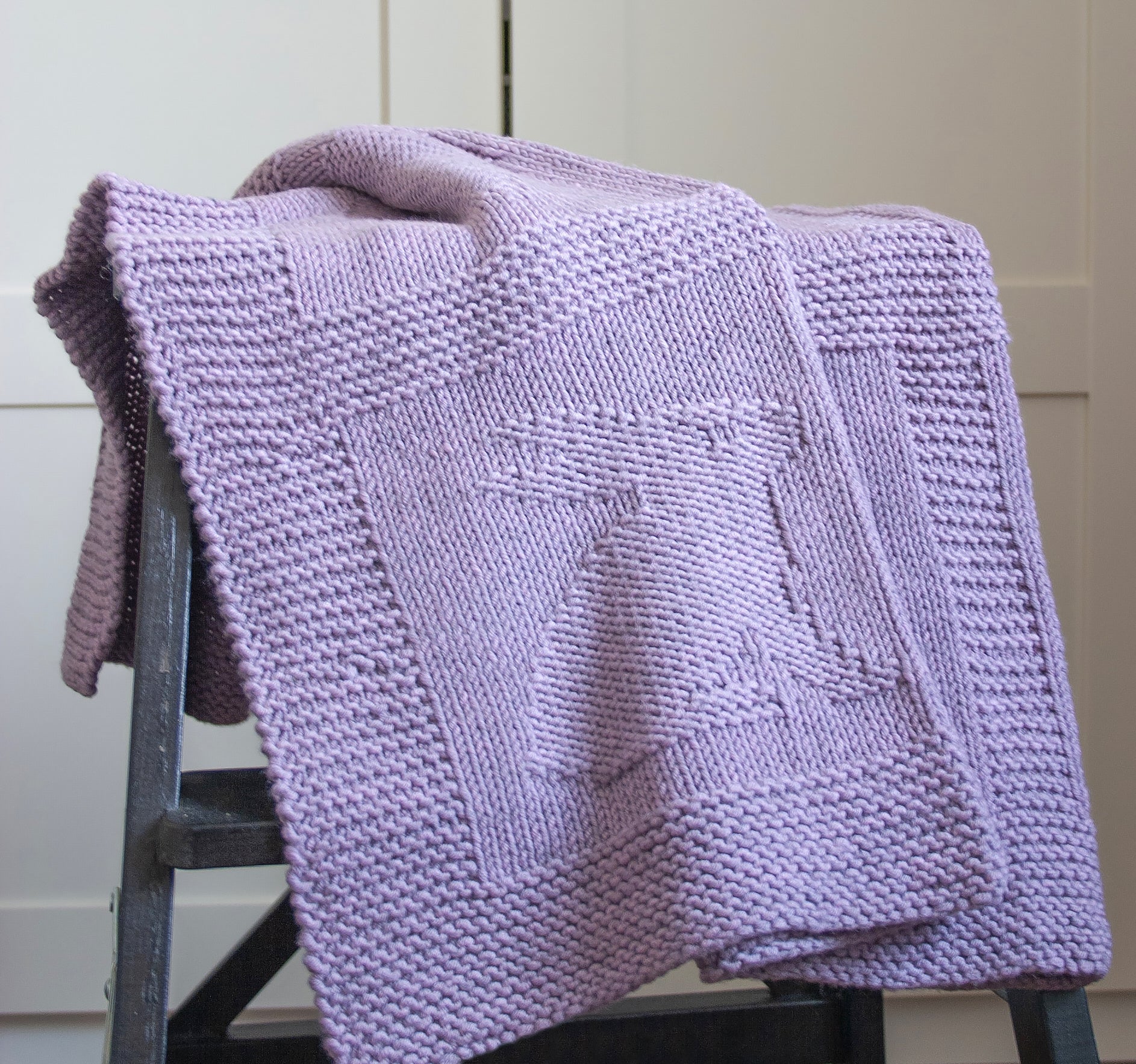 Purple superwash merino wool yarn hand-knitted baby blanket in Hearts & Bunnies knitting pattern