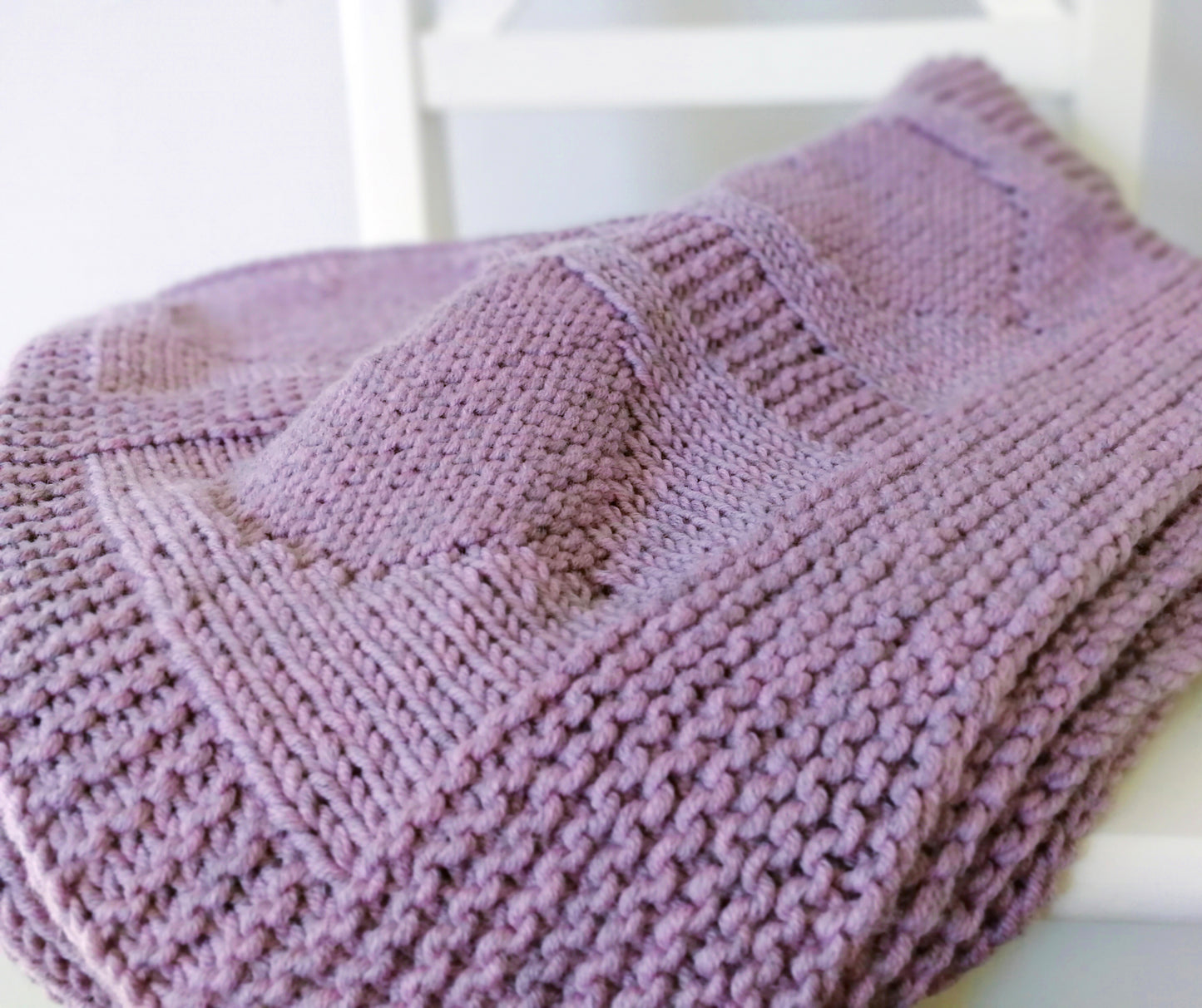 close up for Purple superwash merino wool yarn hand-knitted baby blanket in Hearts knitting pattern
