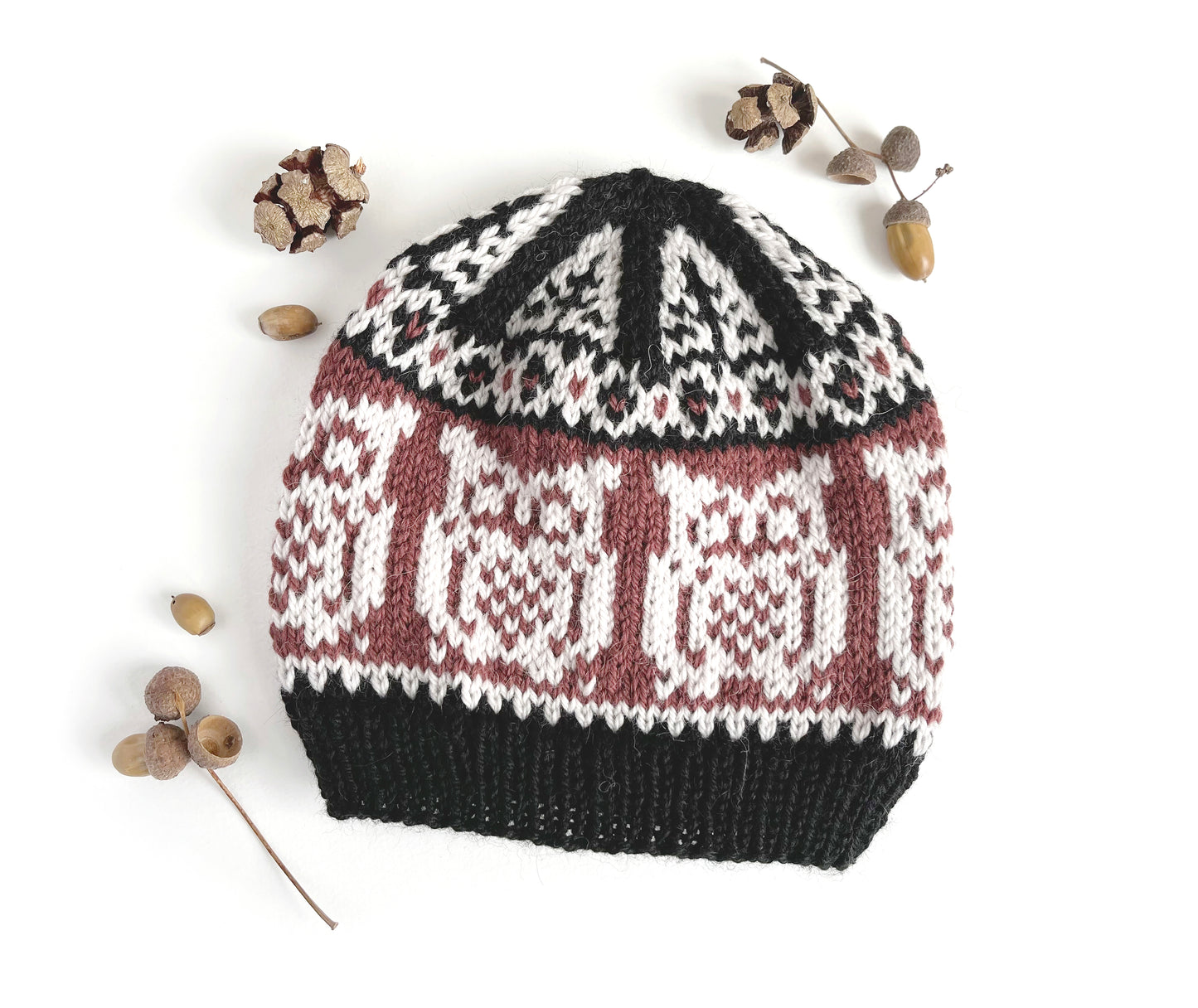 Front view of Owl Selbu hat, featuring an owl motif in black, chalk and bordeaux