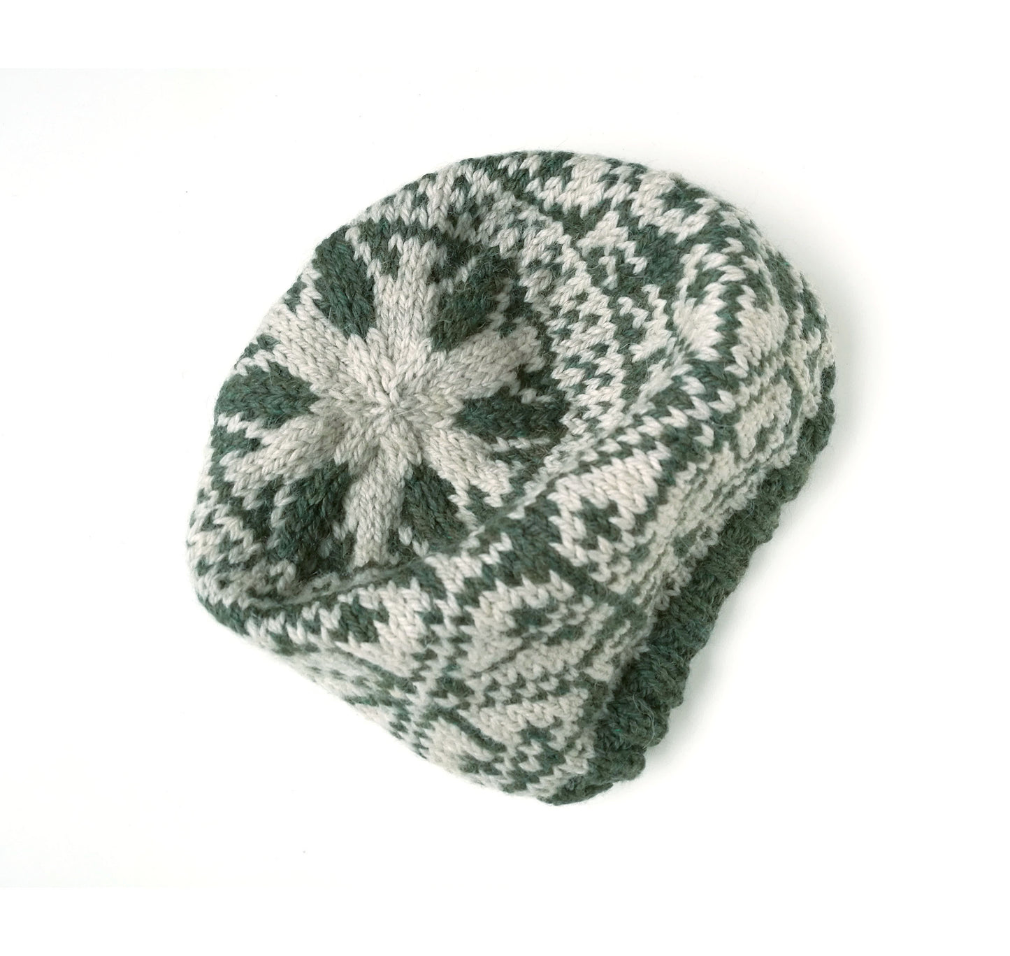 A hand-knit slouchy beanie hat featuring a dark green and light gray snowflake pattern, photographed on a clean white background.