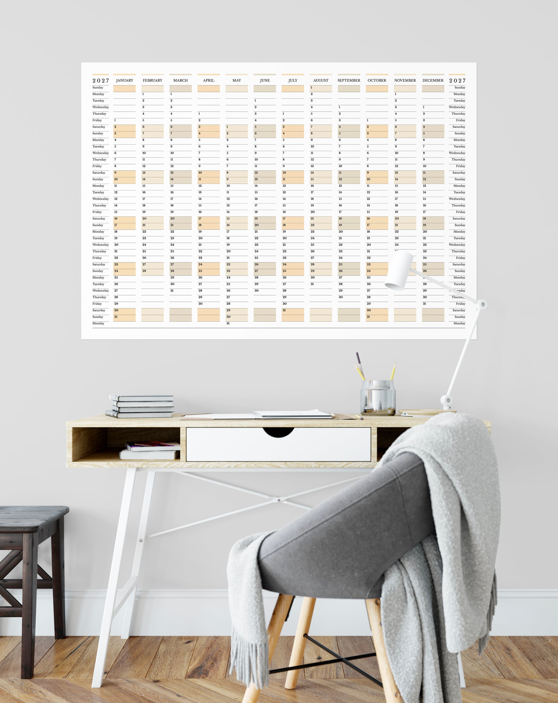 Calendar on a wall above a desk with a chair and decor items.