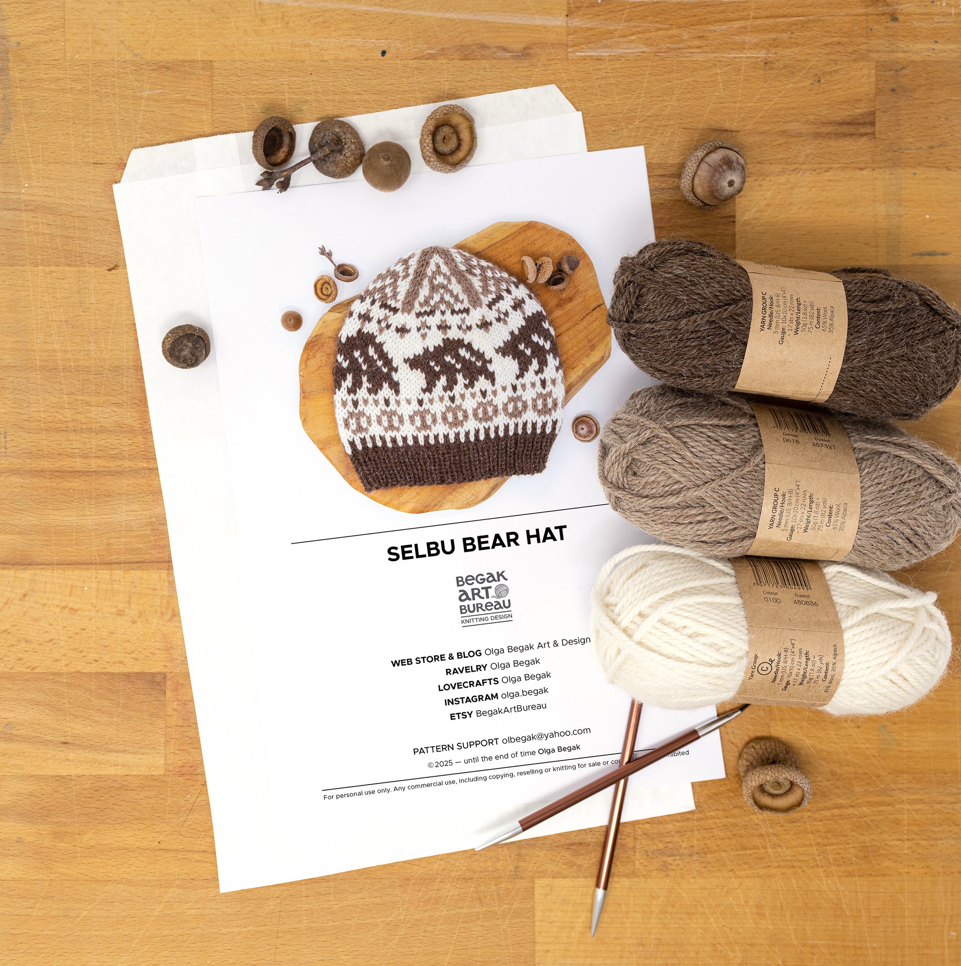 Knitting materials for a Bear Selbu hat on a wooden surface.