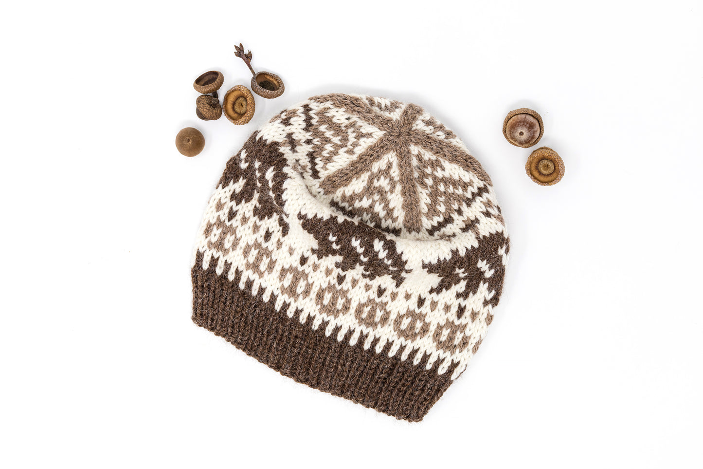 Brown and whie knitted hat with bear motif accompanied with acorns on a white background