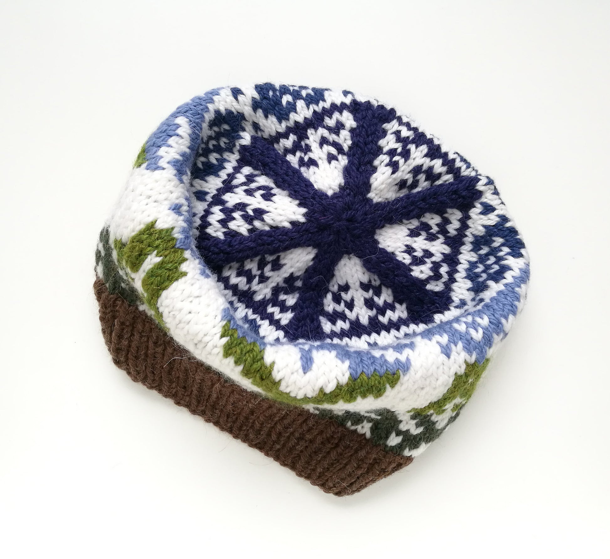 A crown of a green, brown, blue and white hand-knitted Fair Isle beanie hat with a bunny motif