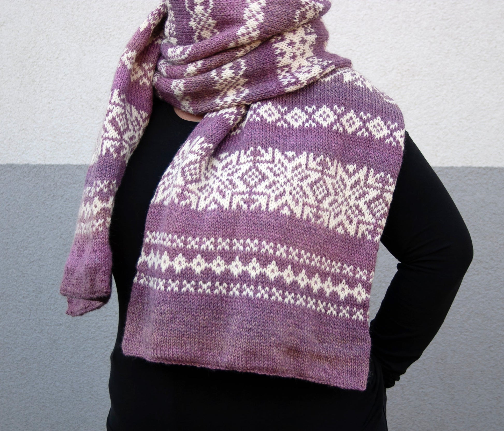 a woman performs a long hand-knitted Fair Isle scarf made from gradient purple and white wool