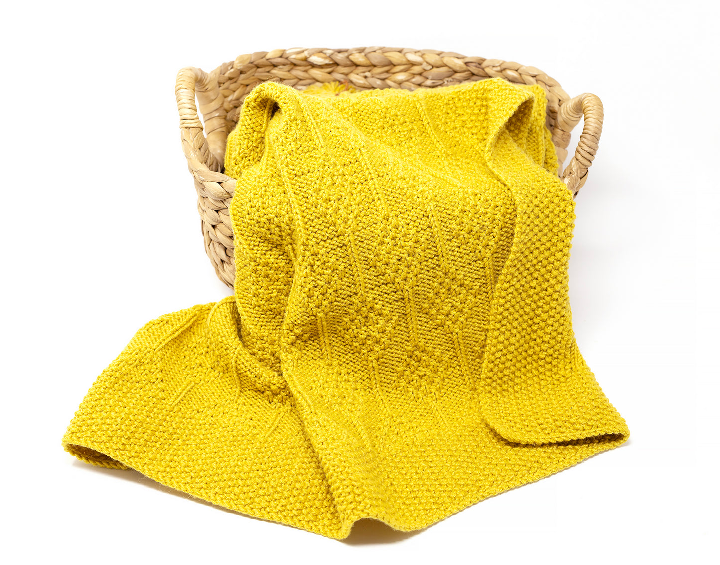 Yellow knit and purl hand-knitted baby blanket in Diamonds pattern folded in a basket