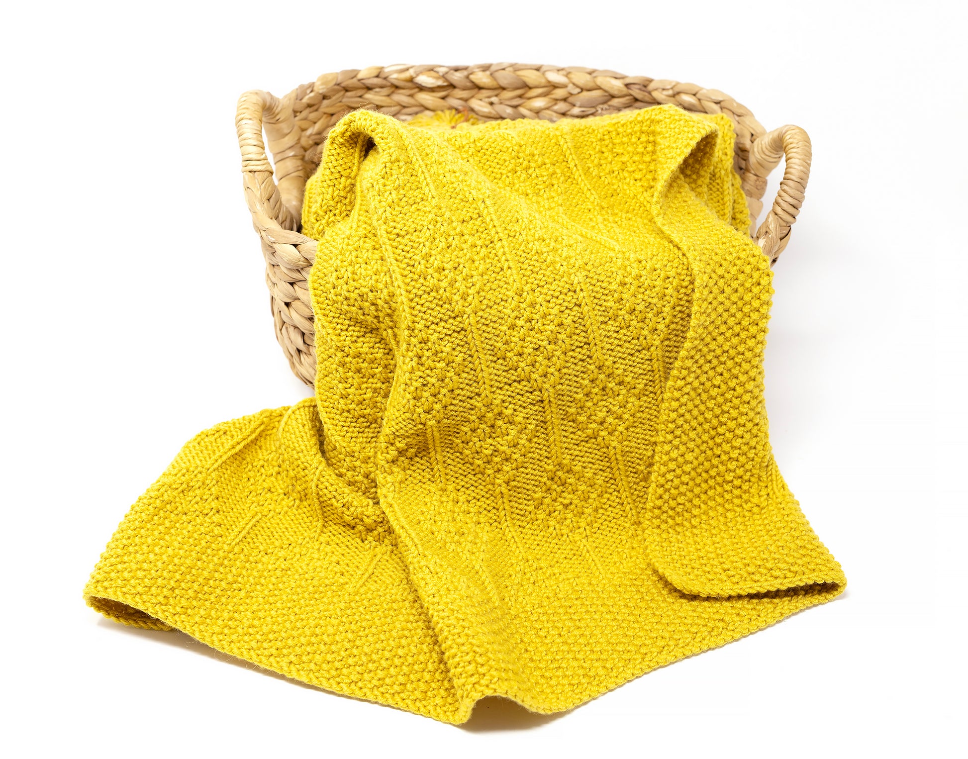 Yellow knit and purl hand-knitted baby blanket in Diamonds pattern folded in a basket