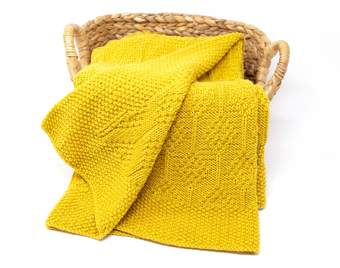 Mustard yellow merino wool hand-knitted baby blanket in Diamonds pattern, folded in a basket