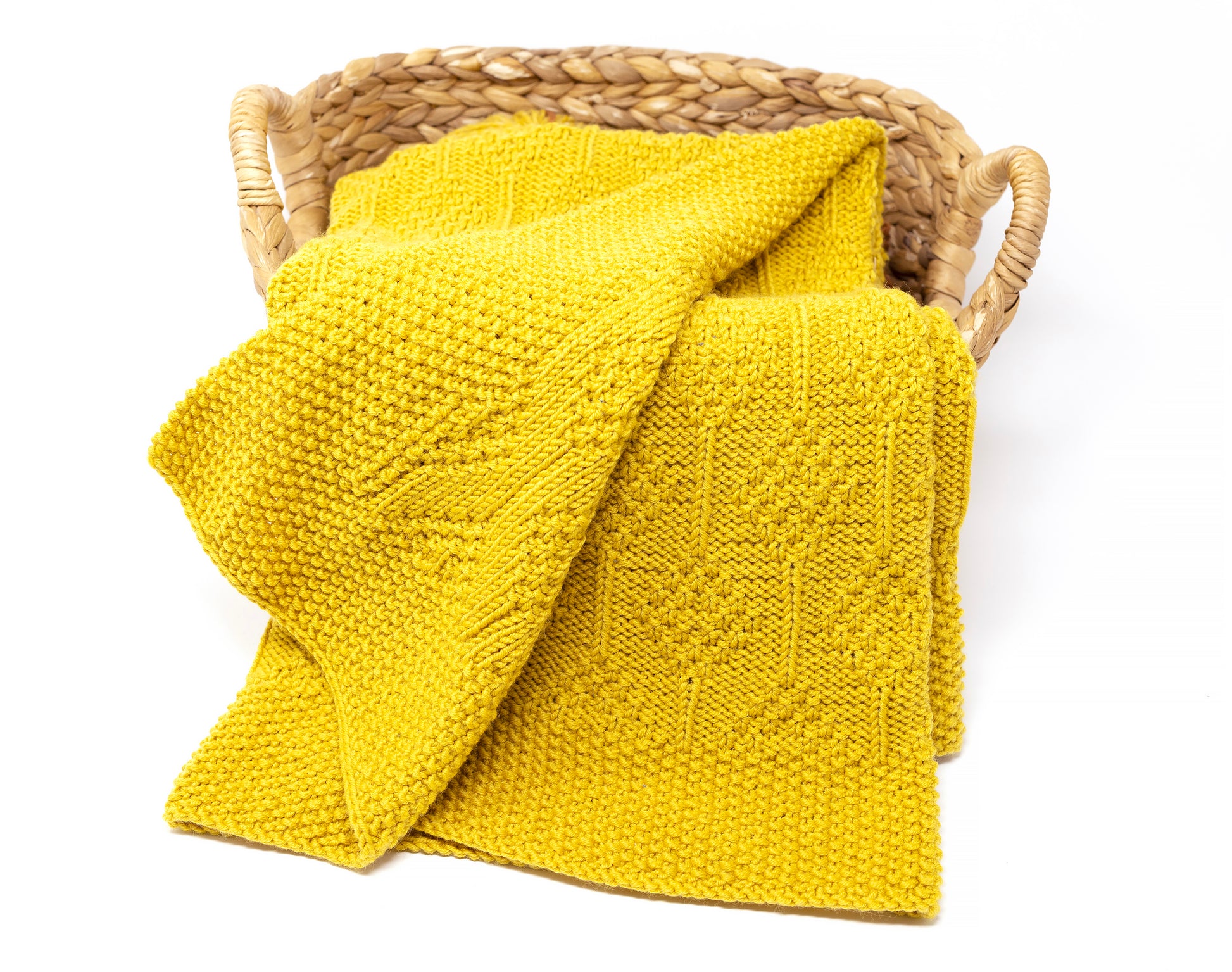 Mustard yellow merino wool hand-knitted baby blanket in Diamonds pattern, folded in a basket