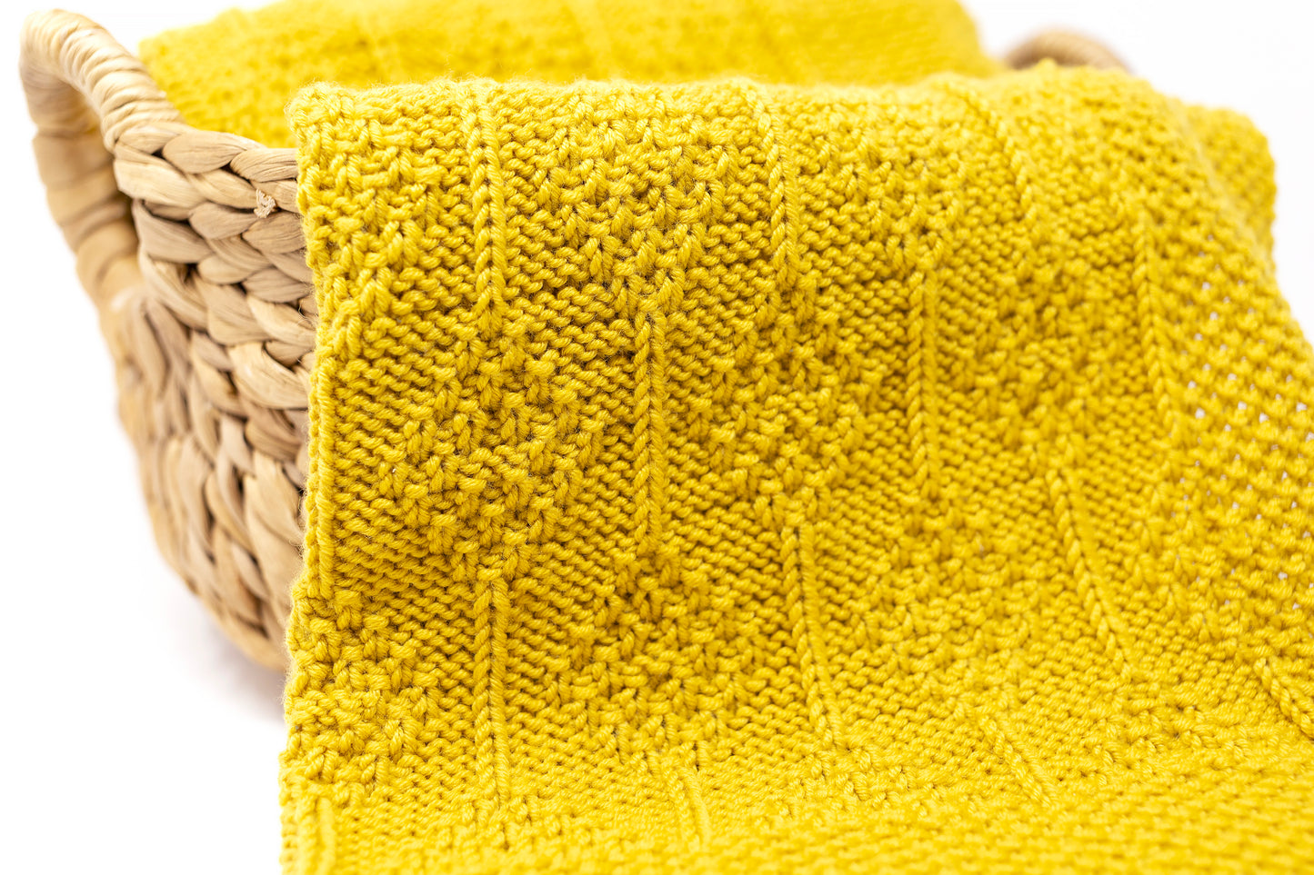 Close up of textured mustard yellow hand-knitted baby blanket in Diamonds pattern
