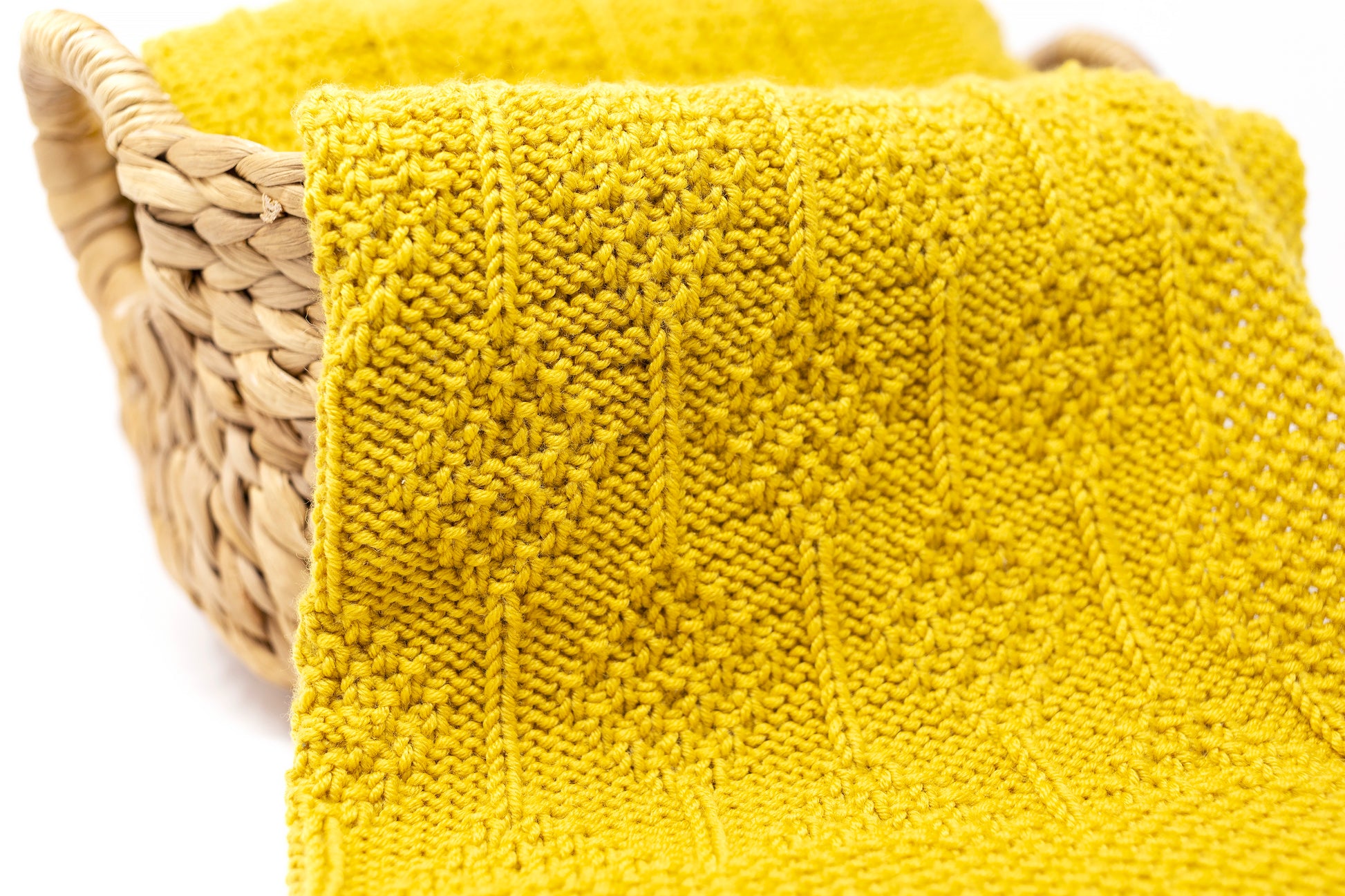 Close up of textured mustard yellow hand-knitted baby blanket in Diamonds pattern