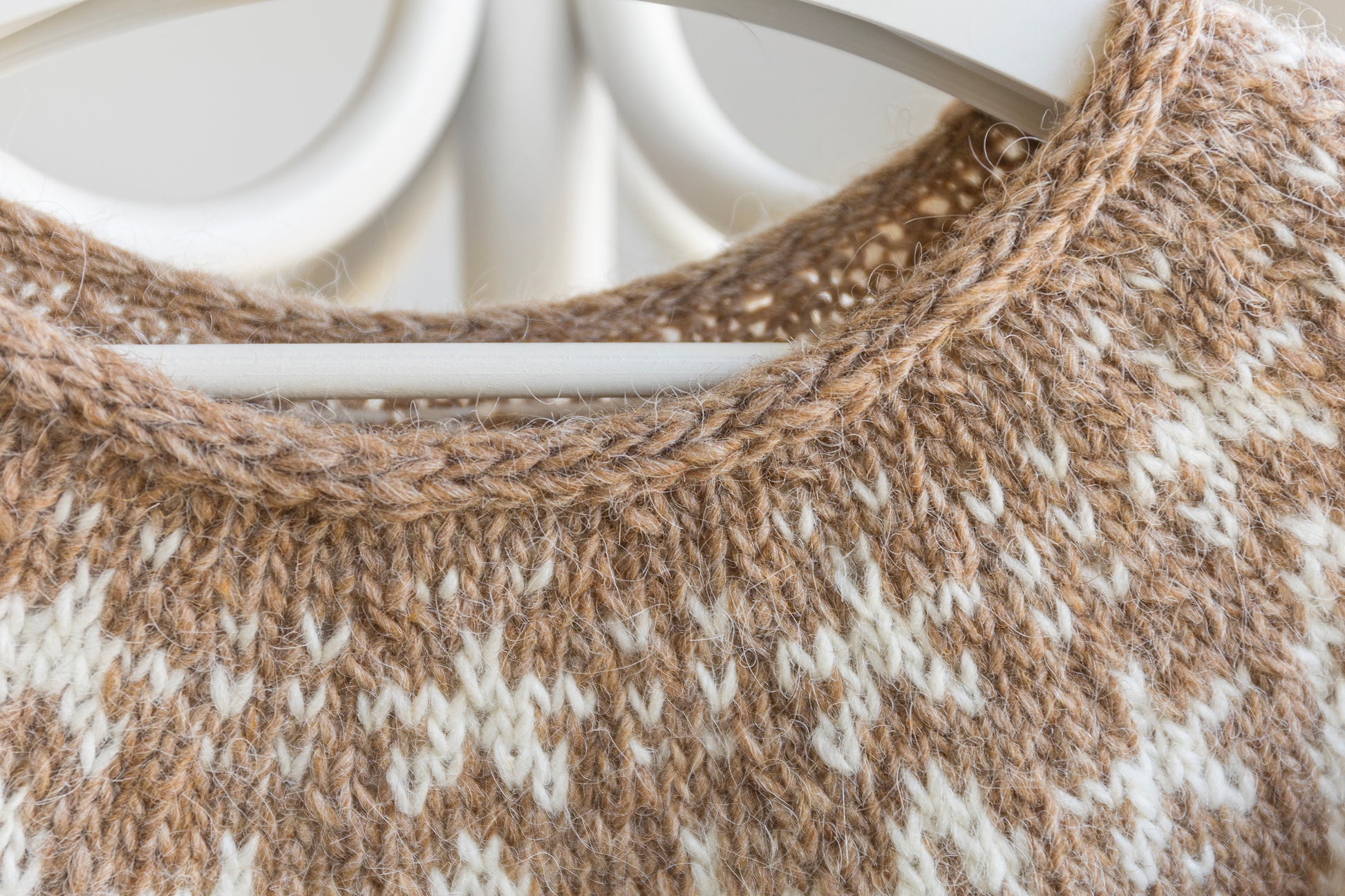 Close-up of a knitted sweater with a pattern on a hanger.