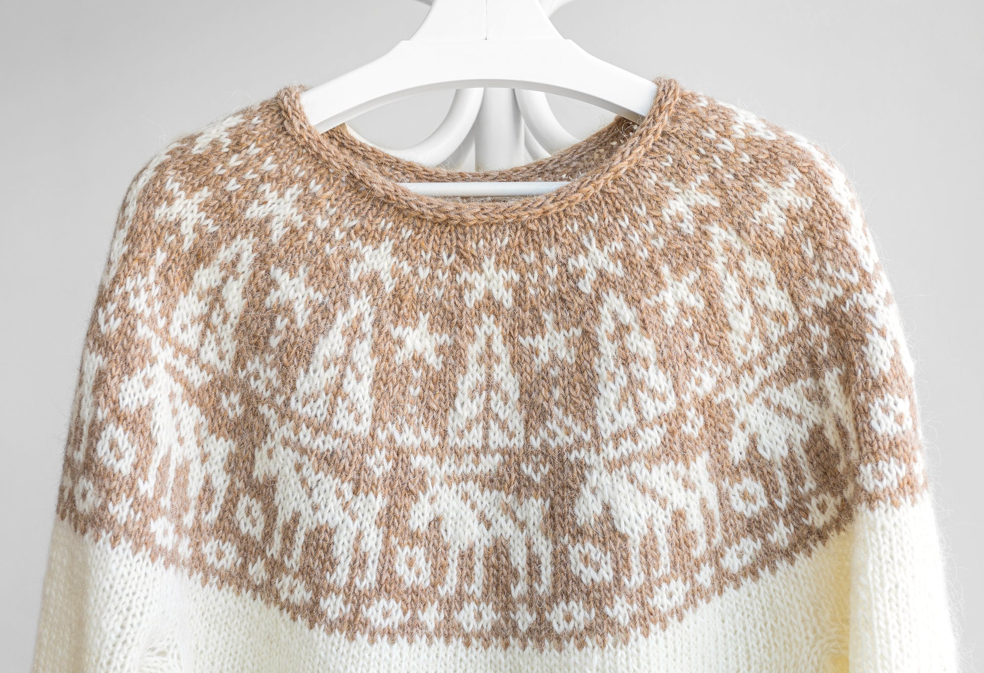 Knitted white sweater with a brown pattern features elk on a white background