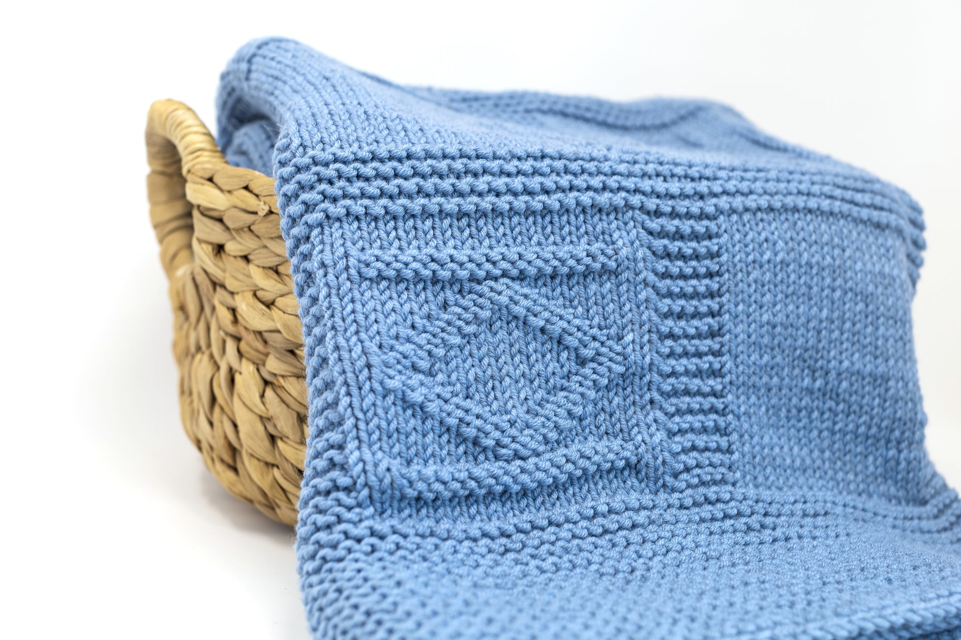 Close up for a blue merino wool hand-knitted baby blanket in geometric pattern