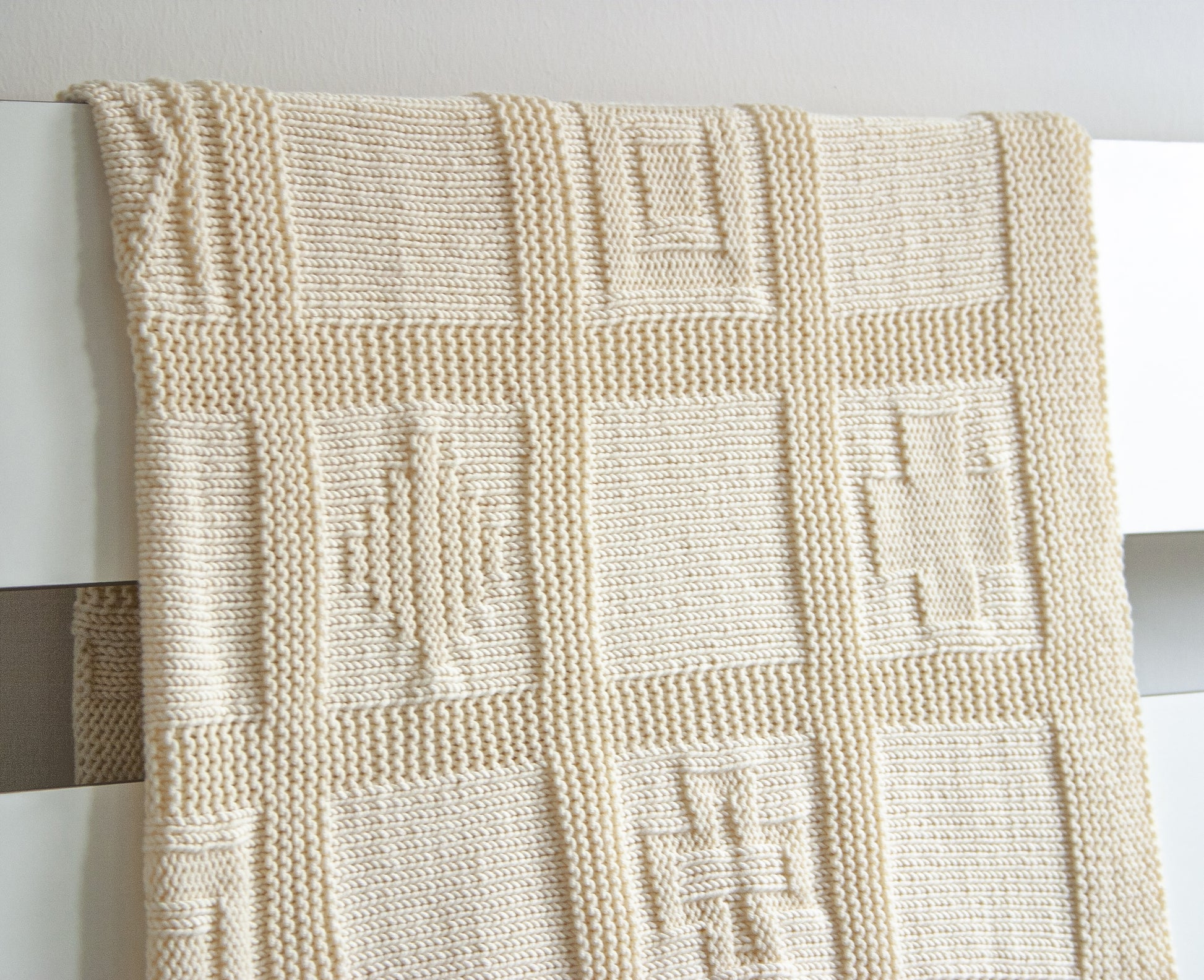 White merino wool hand-knitted baby blanket in geometric pattern