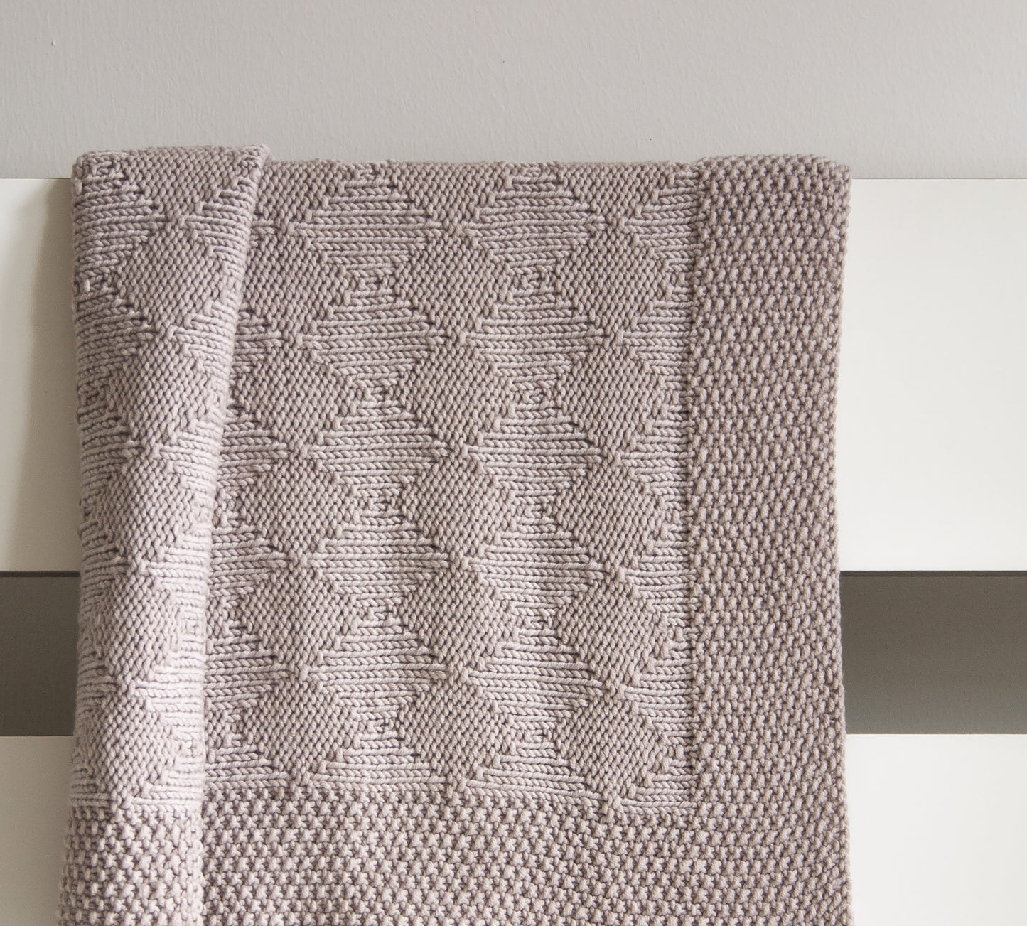 Beige hand-knitted Harlequin baby blanket knitting pattern, beige textured diamond design