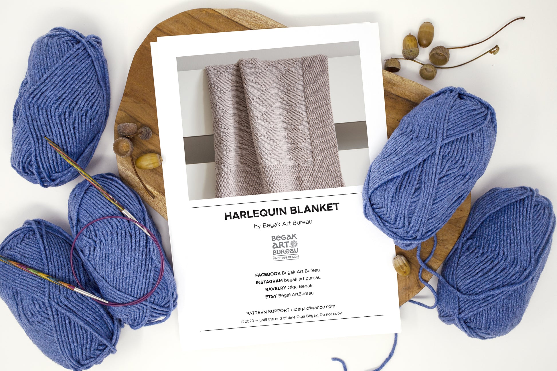 Harlequin baby blanket knitting pattern page and blue yarn balls