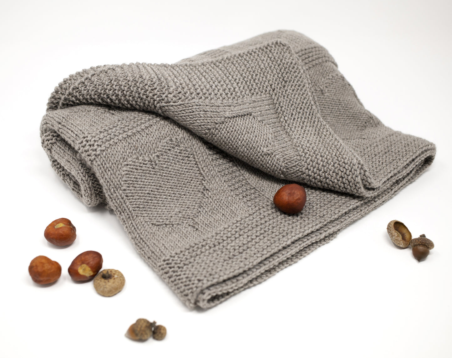 beige superwash merino wool yarn hand-knitted baby blanket in Hearts knitting pattern on a white background