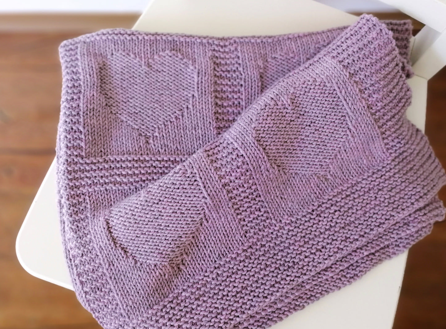 Close up for purple superwash merino wool yarn hand-knitted baby blanket in Hearts knitting pattern