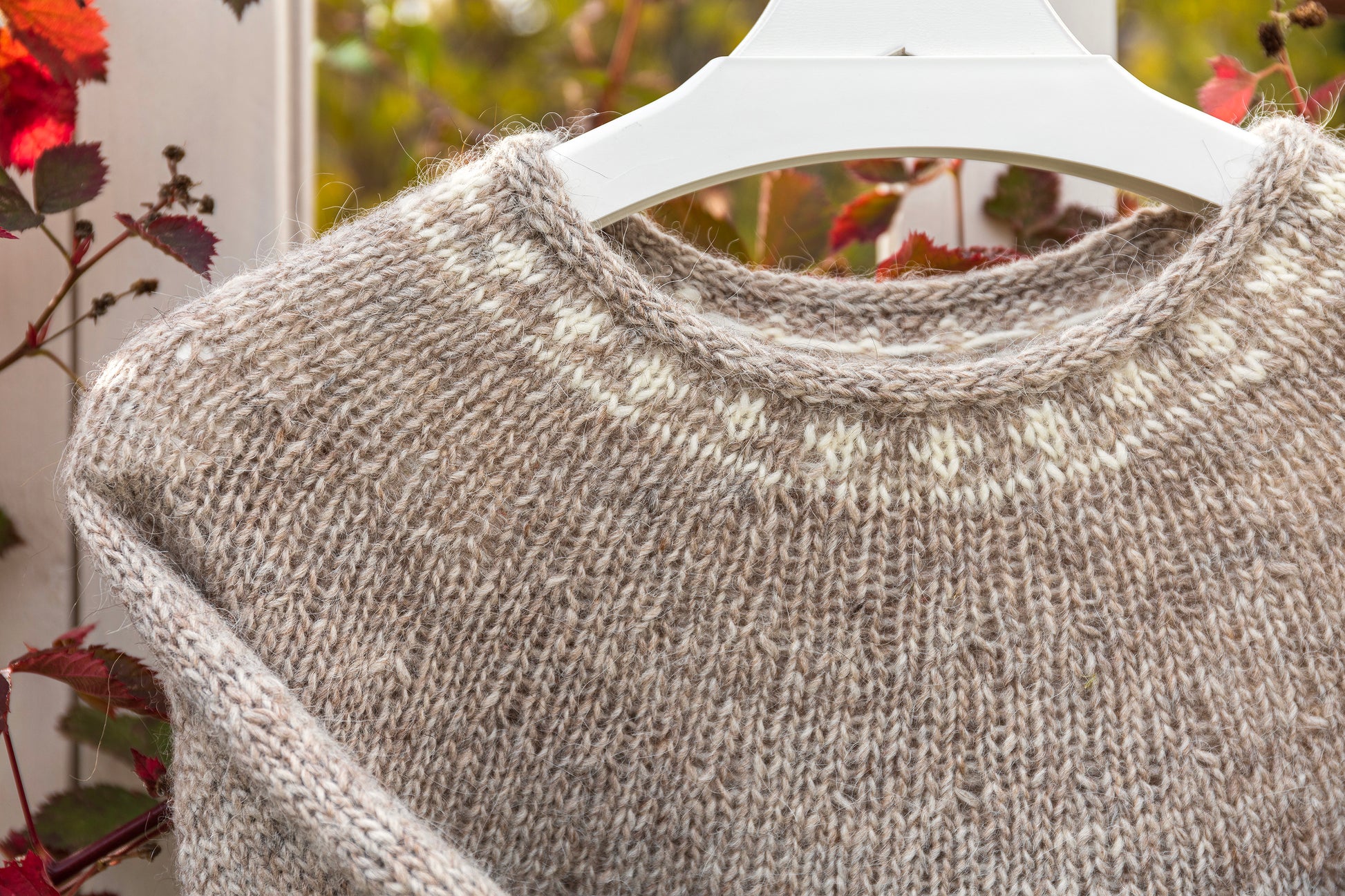 Close-up of Helga icelandic lopapeysa sweater on a hanger with a blurred natural background