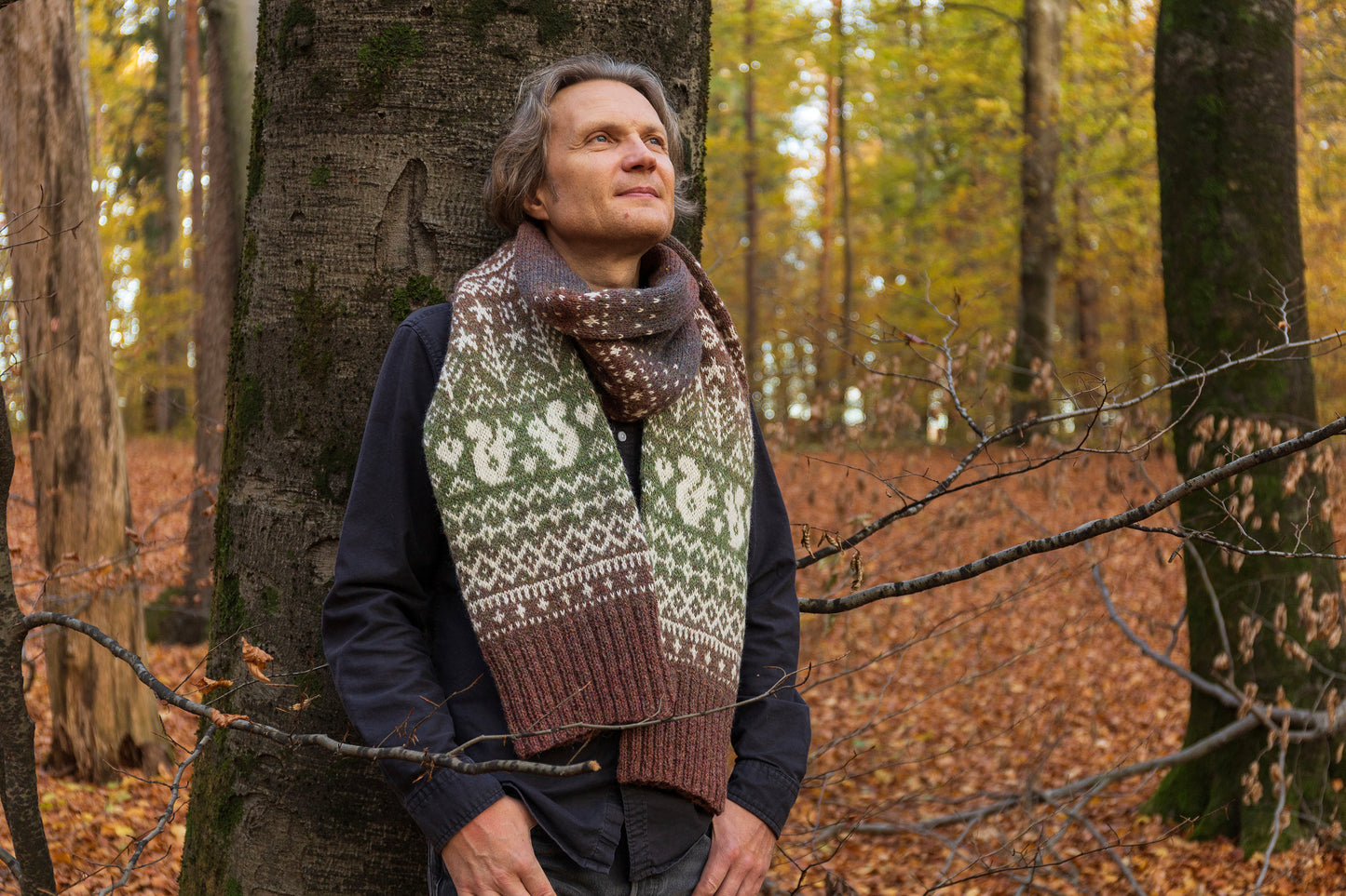 Man wearing Lahemaa squirrel Fair Isle scarf standing in a forest