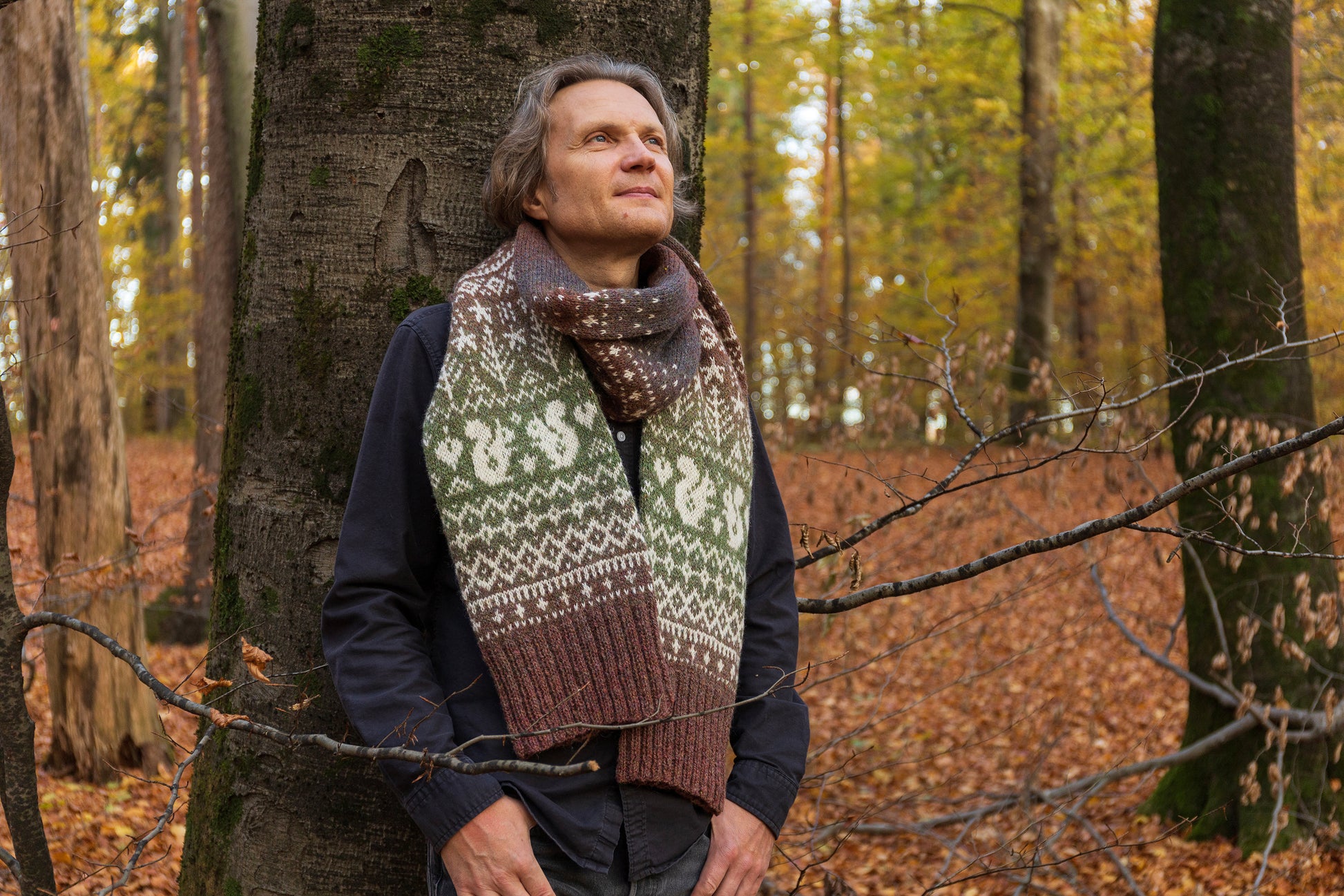 Man wearing Lahemaa squirrel Fair Isle scarf standing in a forest