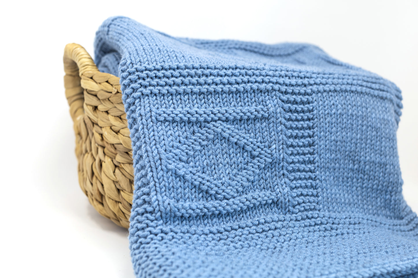 close up for blue merino wool hand-knitted baby blanket in geometric knitting pattern