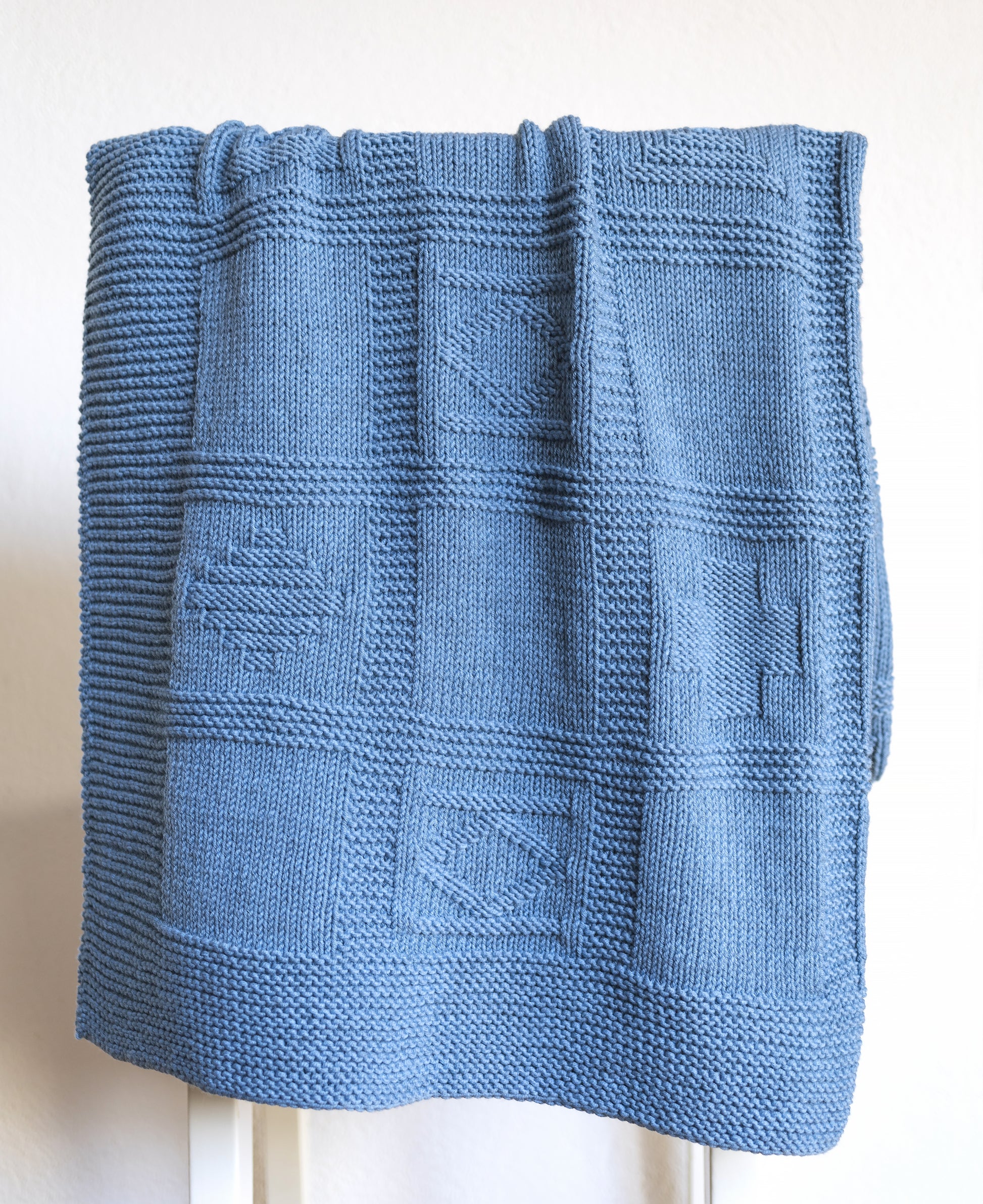 details of blue merino wool yarn hand-knitted baby blanket in geometrical knitting pattern