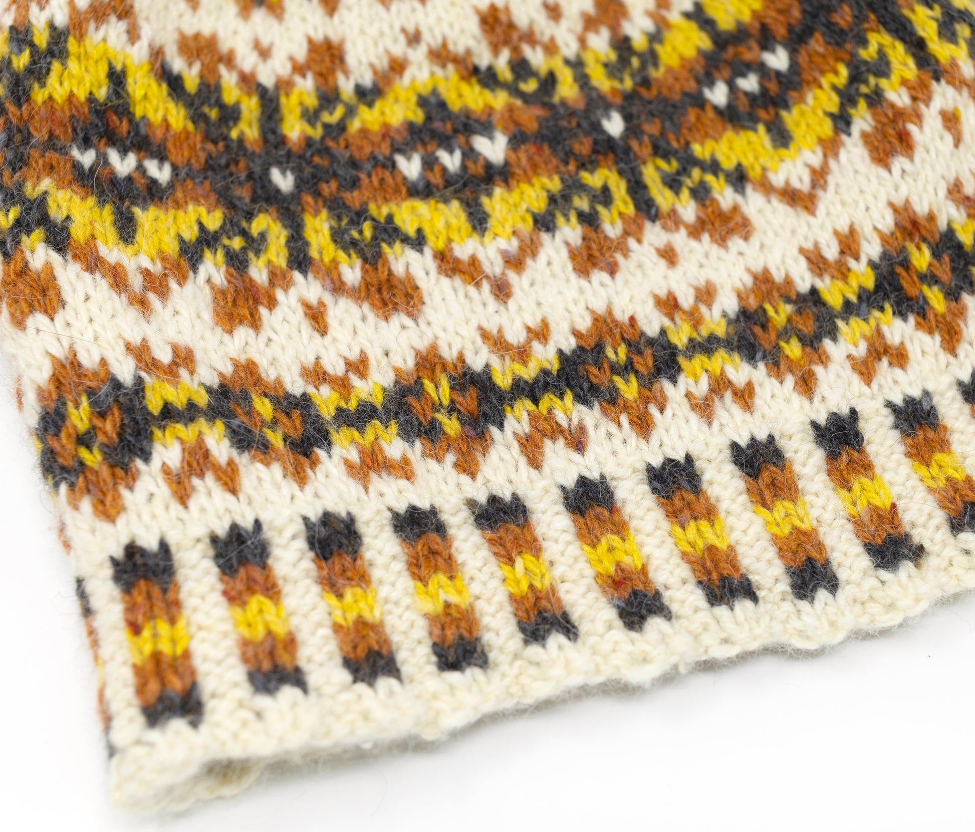 close up for yellow, orange, black and white wool hand-knitted Fair Isle beanie hat
