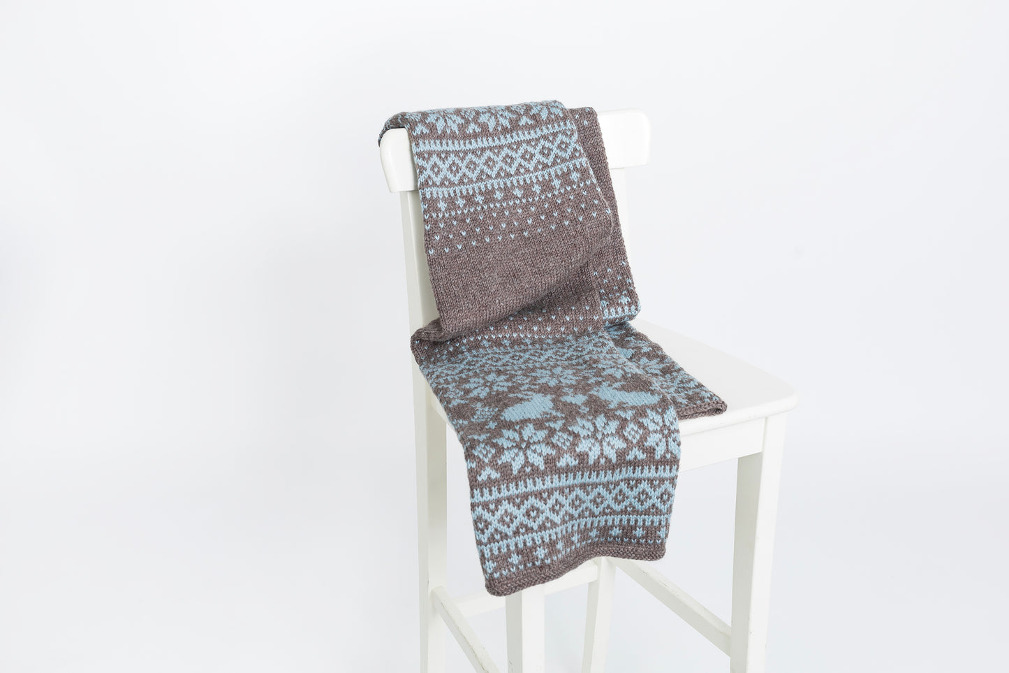 Brown and blue wool long hand-knitted Fair Isle scarf in Bunny Rabbits knitting pattern on a chair