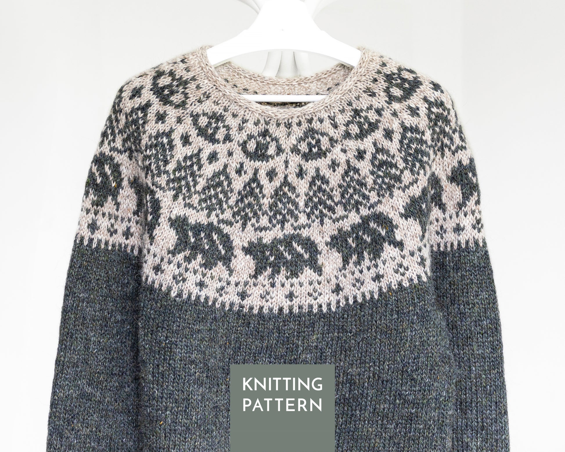 A knitted sweater shown on a white hanger against a light gray background, with a dark gray lower body and a cream and dark gray Fair Isle yoke pattern. A gray label at the bottom reads 'KNITTING PATTERN'.