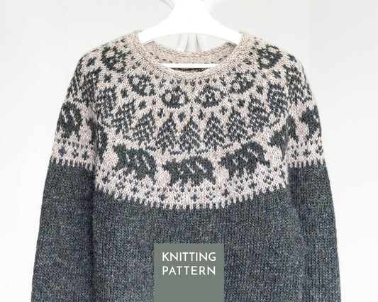 A knitted sweater shown on a white hanger against a light gray background, with a dark gray lower body and a cream and dark gray Fair Isle yoke pattern. A gray label at the bottom reads 'KNITTING PATTERN'.
