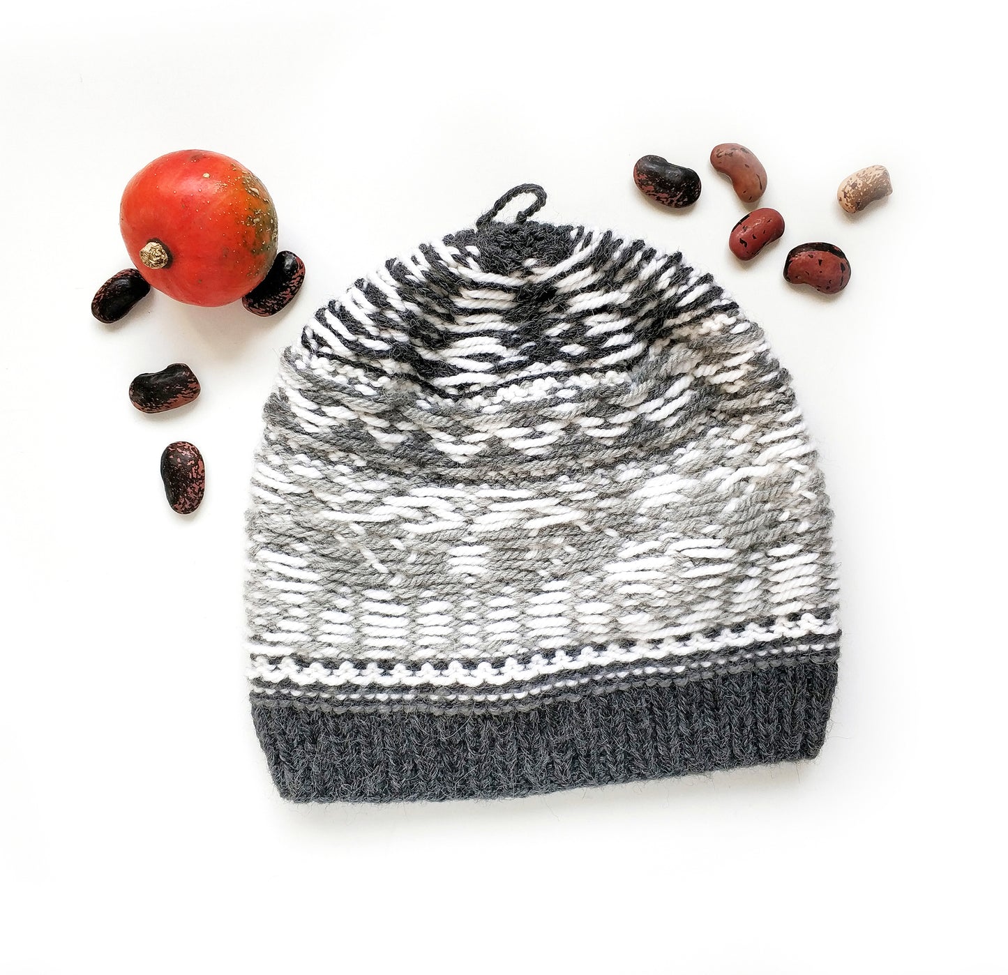A gray and white wool hand-knitted Fair Isle hat with a moose motif displayed inside out