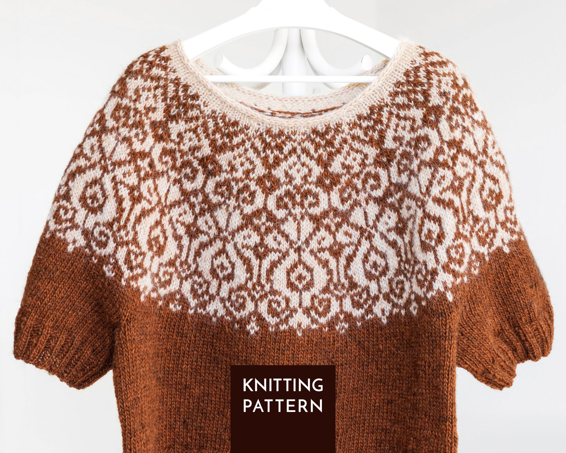 A brown and cream knitted sweater with a Fair Isle pattern, shown hanging on a white hanger against a white background. A dark brown label at the bottom reads 'KNITTING PATTERN'.
