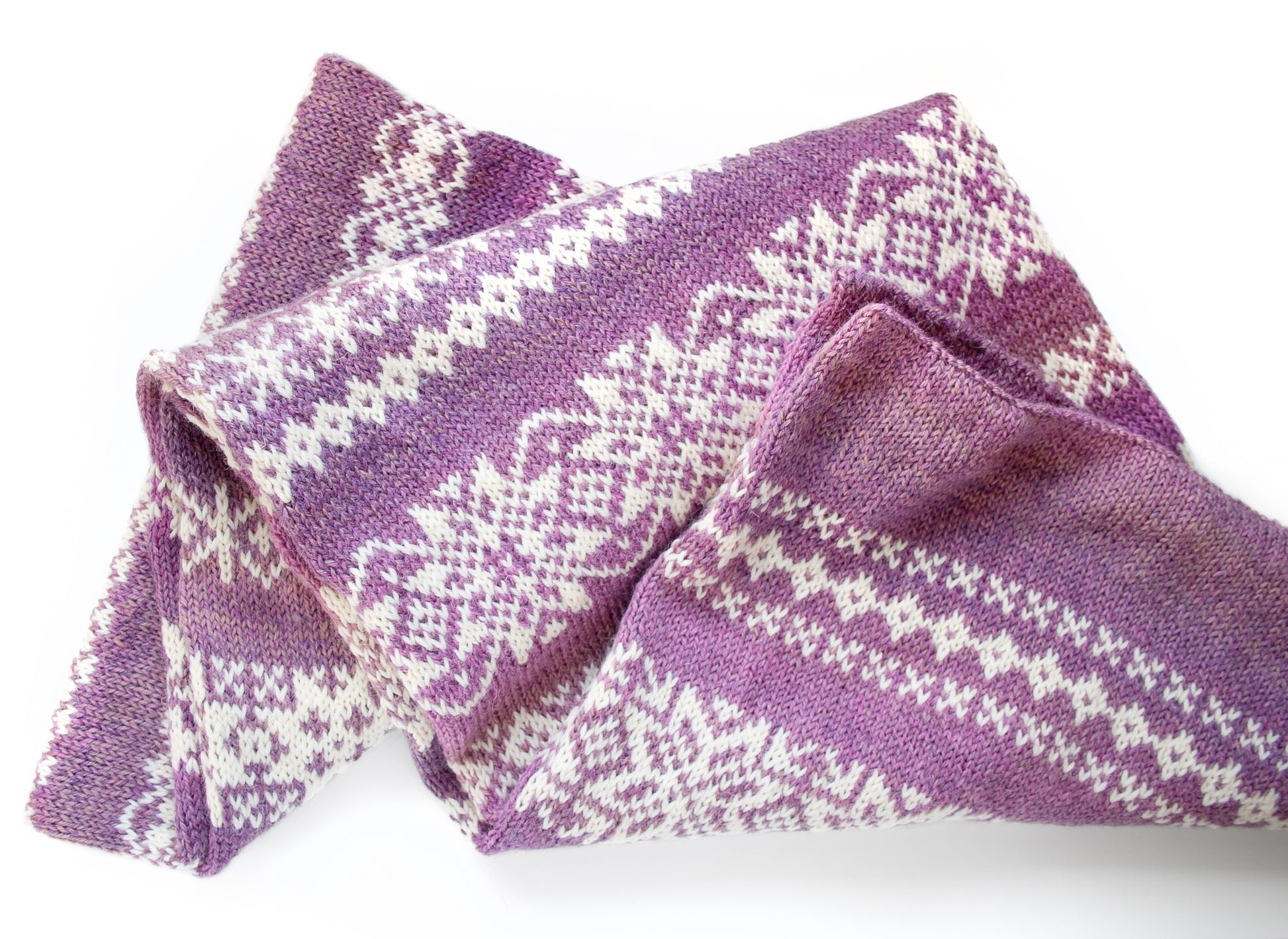 Close-up of Norrsken Fair Isle hand-knitted gardient purple scarf with white snowflakes pattern on a white background