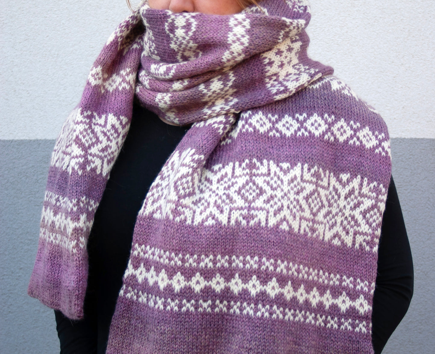 a woman performs gradient purple and white wool hand-knitted Fair isle scarf in snowflake knitting pattern