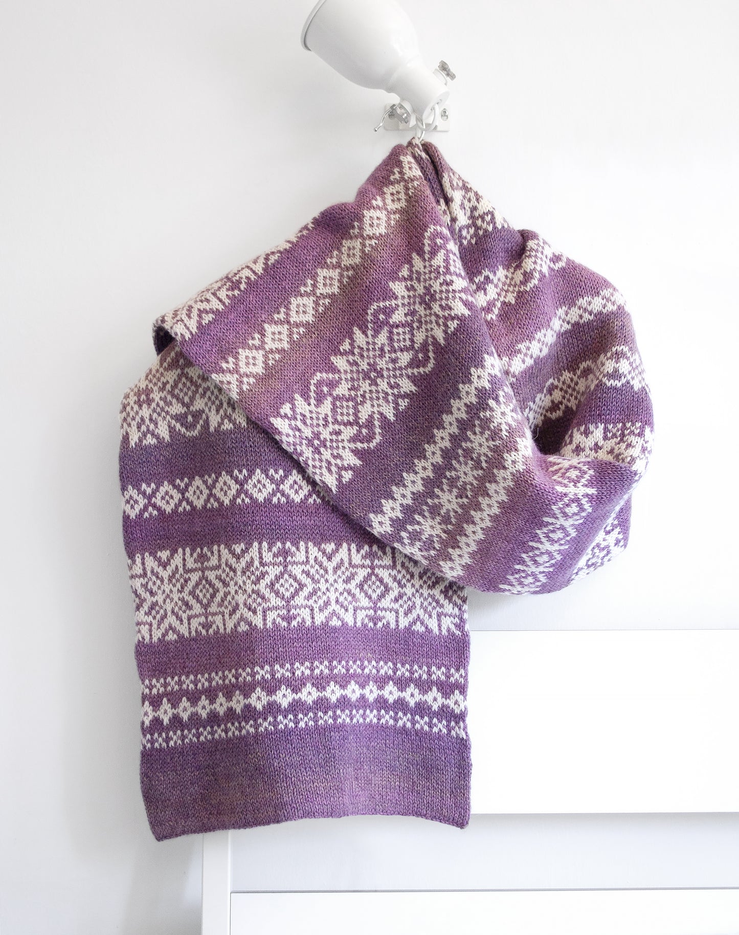 Purple and white patterned knitted scarf on a white background