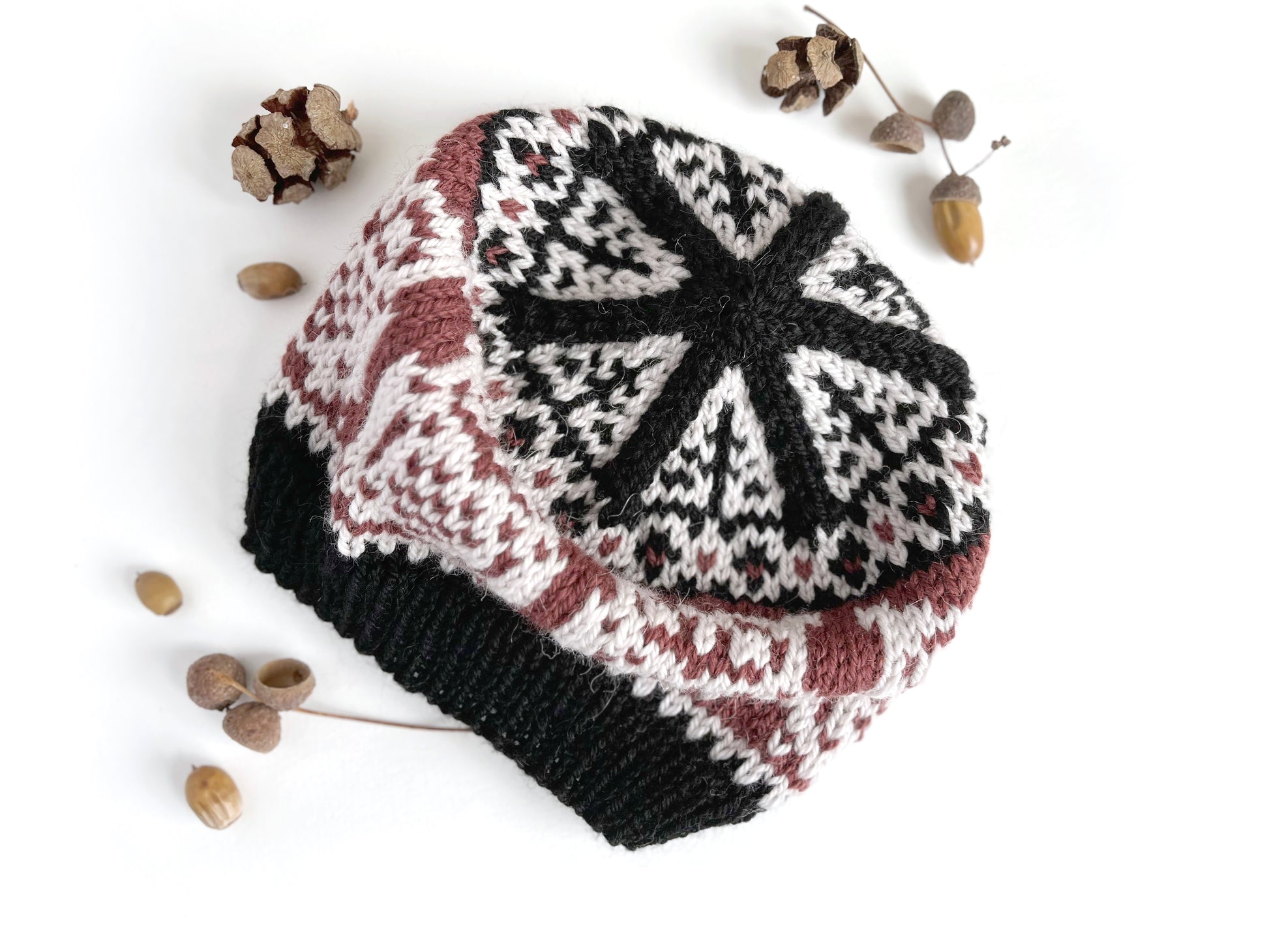 A crown of Owl Selbu hat, featuring an owl motif in black, chalk and bordeaux