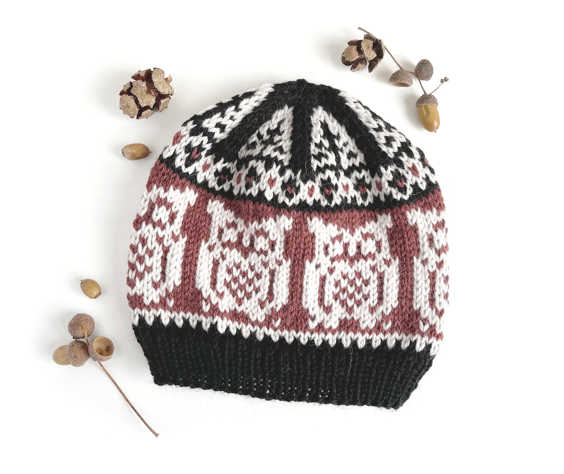 Front view of Owl Selbu hat, featuring an owl motif in black, chalk and bordeaux