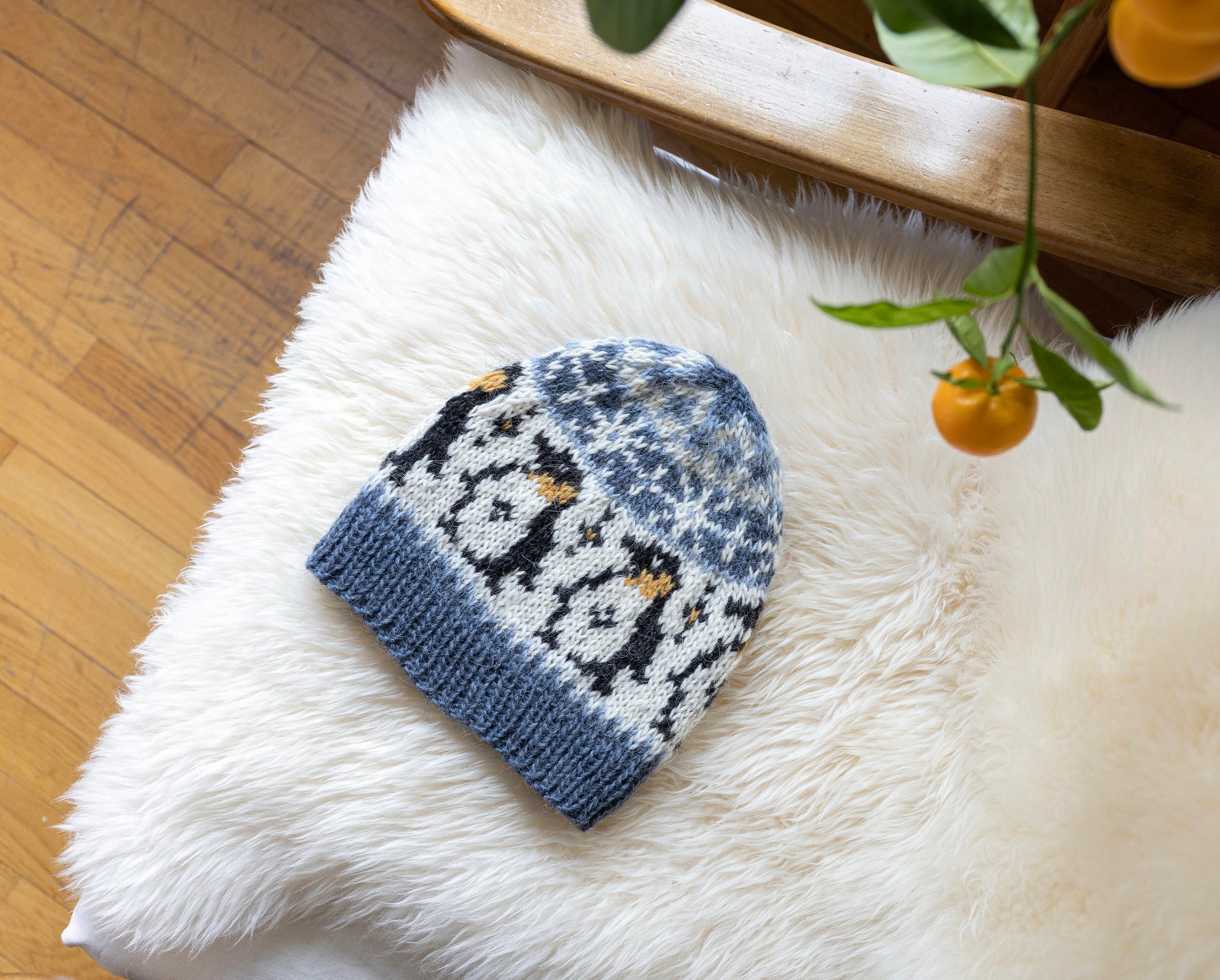 Penguin Fair Isle hat displayed on a white fur armchair