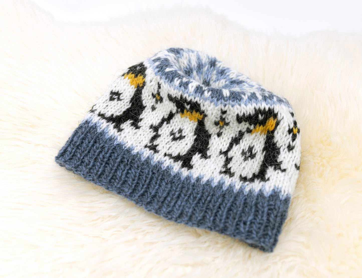 Close-up of a blue, white, black and yellow Fair Isel hat featuring penguins motif
