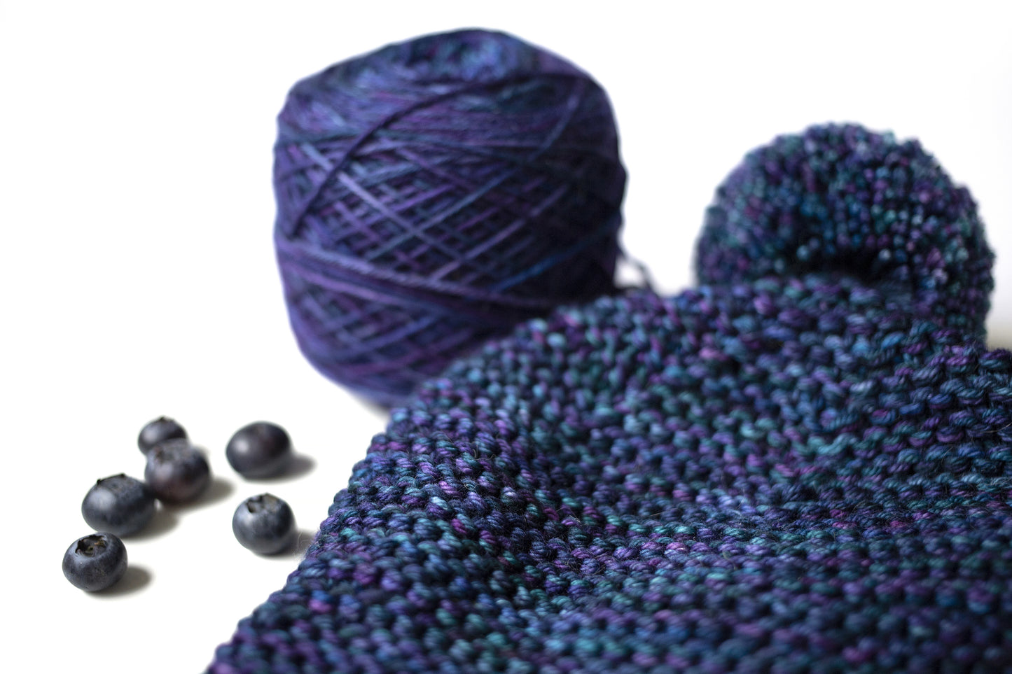 close up of a blue and purple gradient wool garter stitch hand-knitted pom pom hat