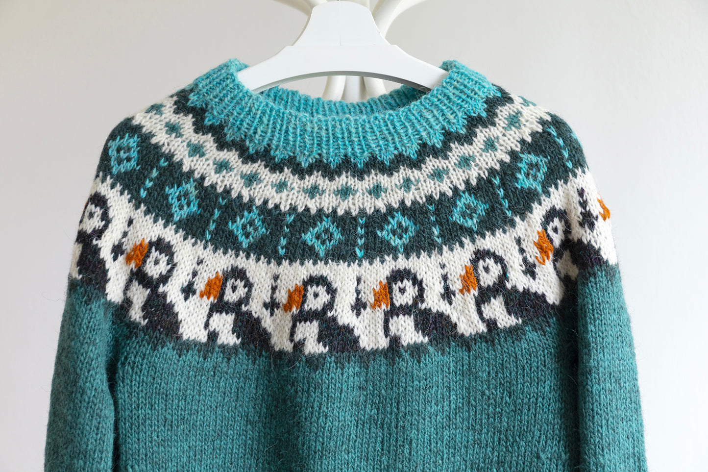 Close up of turquoise, white and black pure Icelandic wool hand-knitted lopapeysa sweater in Puffins design