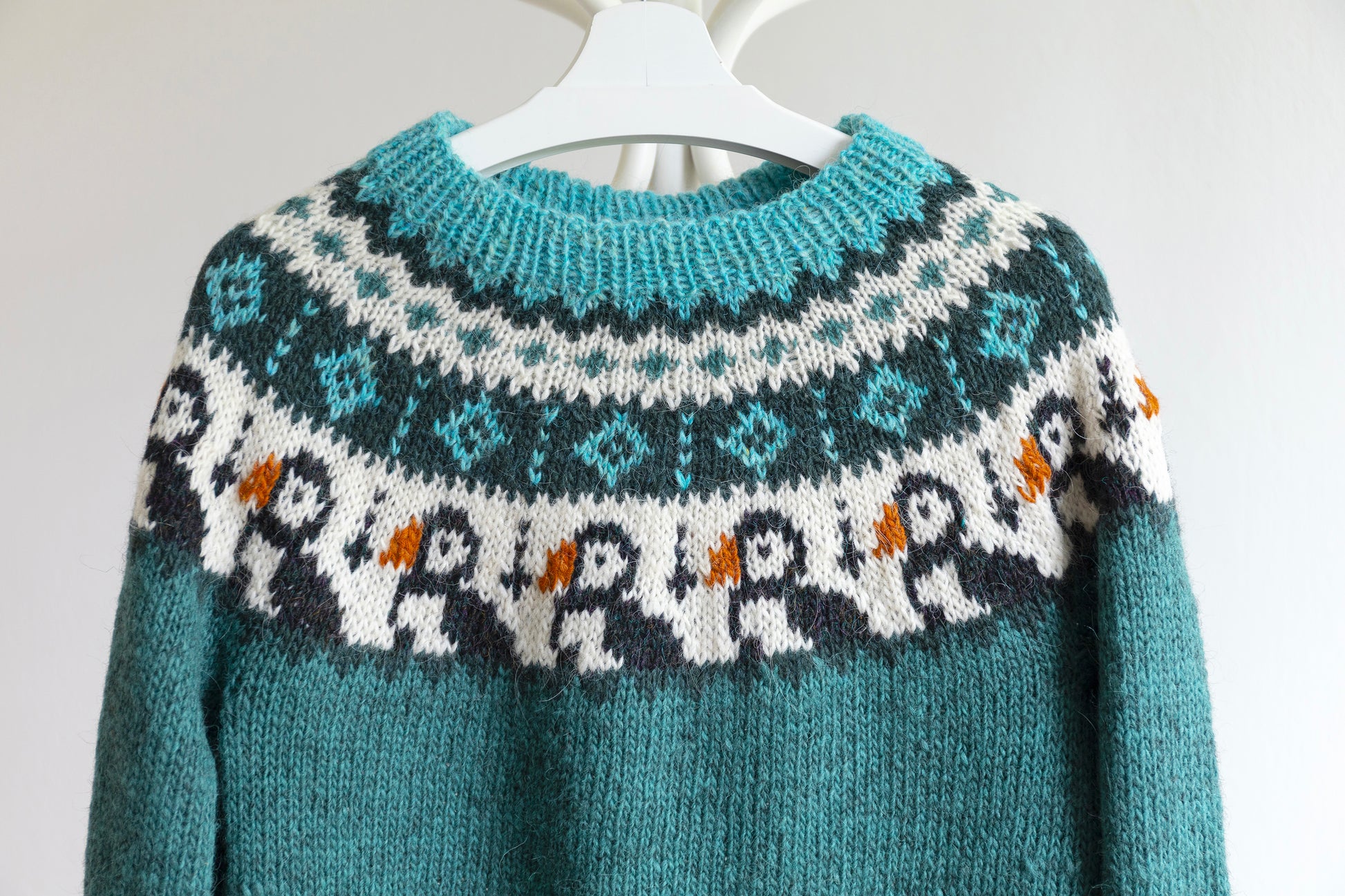 Close up of turquoise, white and black pure Icelandic wool hand-knitted lopapeysa sweater in Puffins design