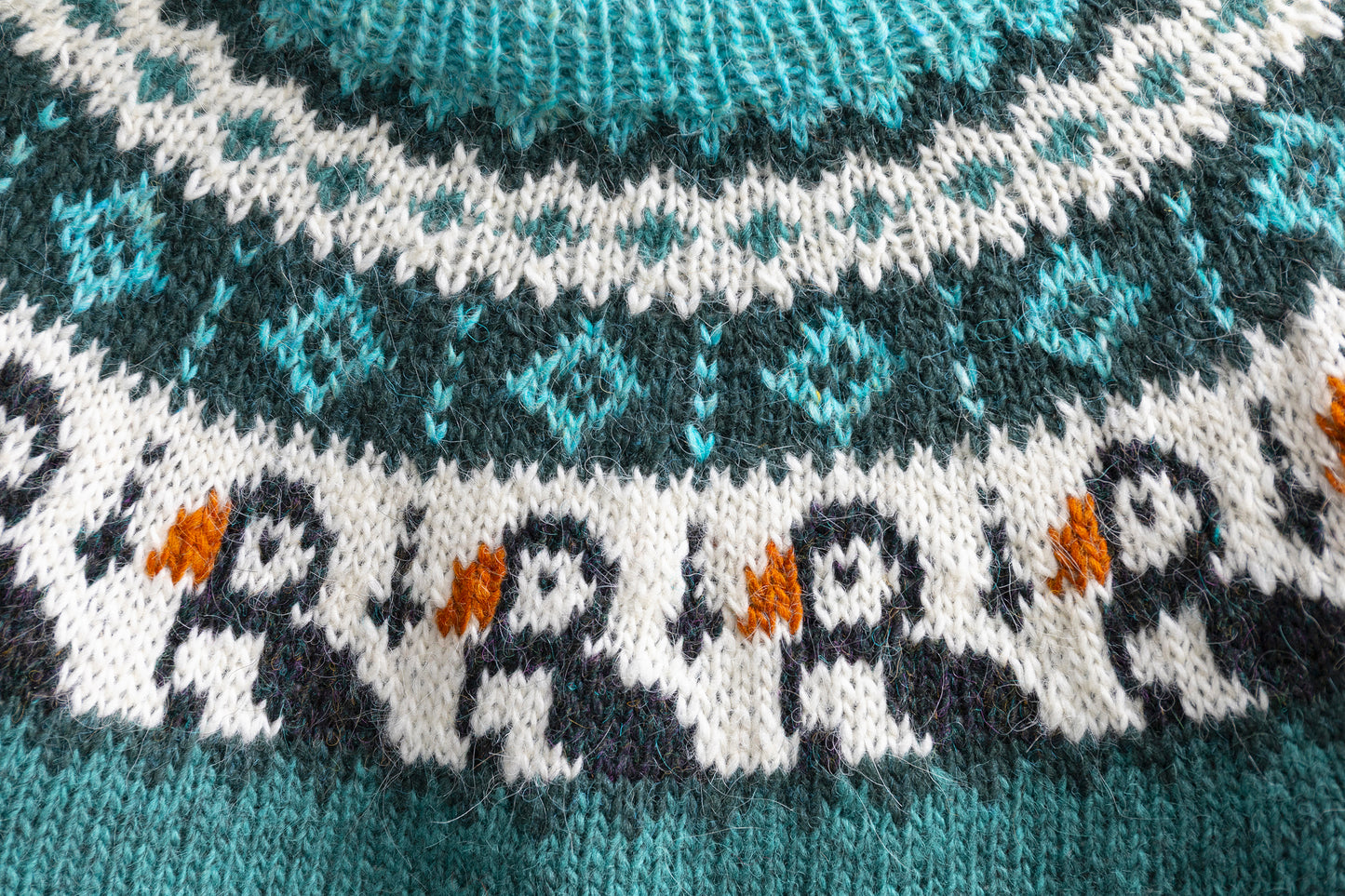 Close-up of a yoke of turquoise, white and black pure Icelandic wool hand-knitted lopapeysa sweater features Puffins