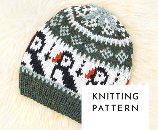 A knitted hat with a puffin design, primarily in green and white colors, with a textured brim.