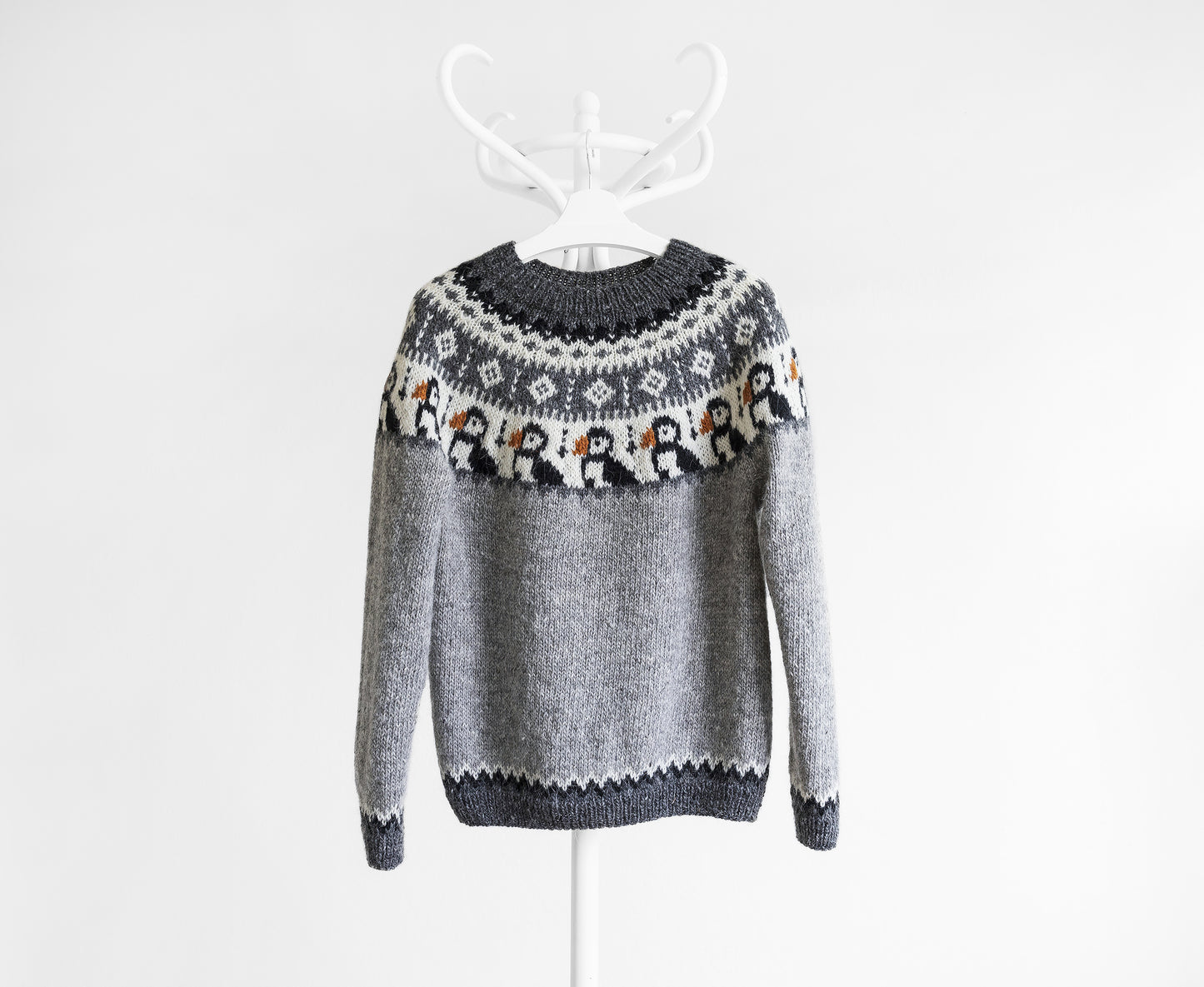 A gray knit sweater with a dark gray crew neck, patterned yoke featuring puffins and geometric motifs, and a dark gray hem and cuffs, displayed on a white hanger against a white background.