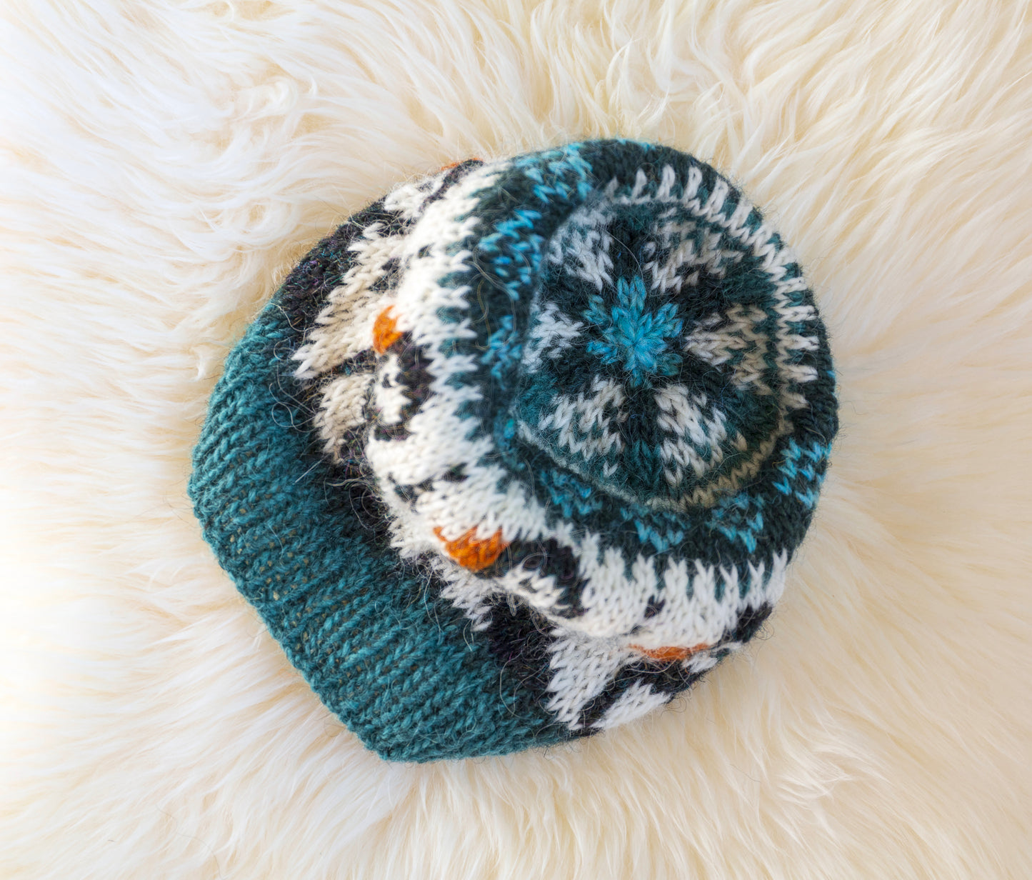 a hand-knitted wool hat with a geometric pattern featuring puffins in blue, black, and brown colors on a white background.